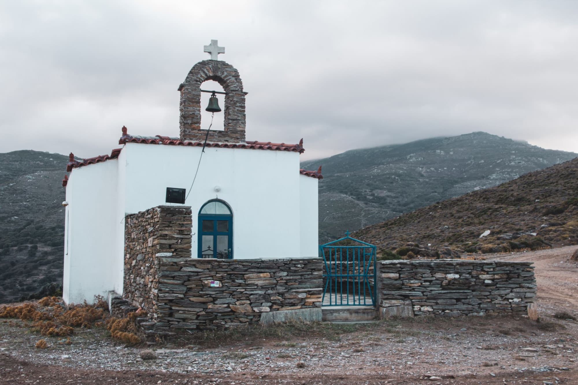 A quaint small chapel in the Andros countryside surrounded by mountains.