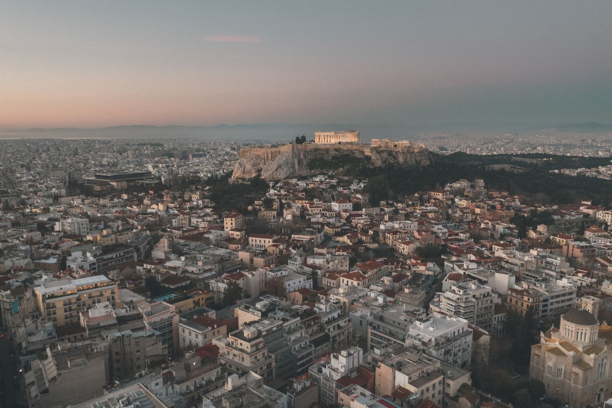 Stunning aerial panorama of Athens showcasing Acropolis at sunset.