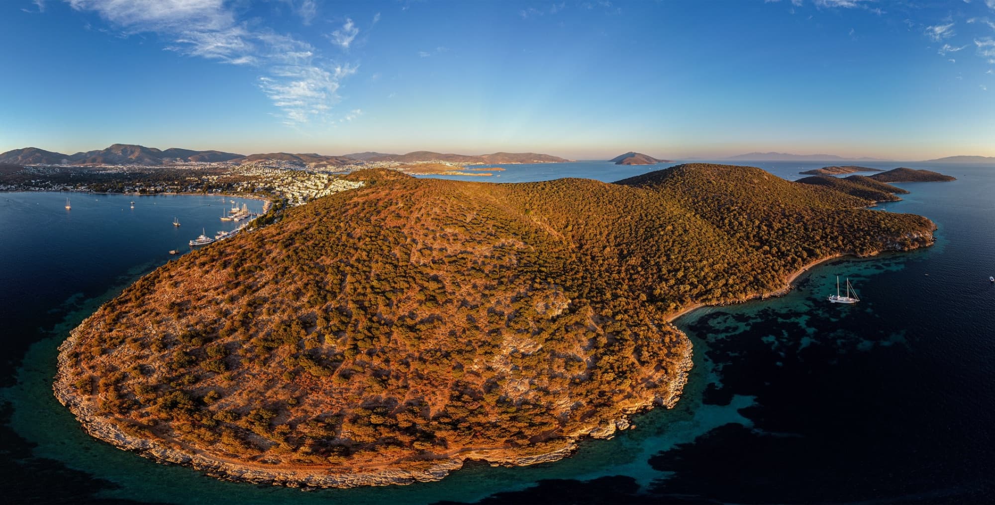 Breathtaking aerial view of Bodrum's coastline, highlighting vibrant landscapes and shimmering sea during sunrise.