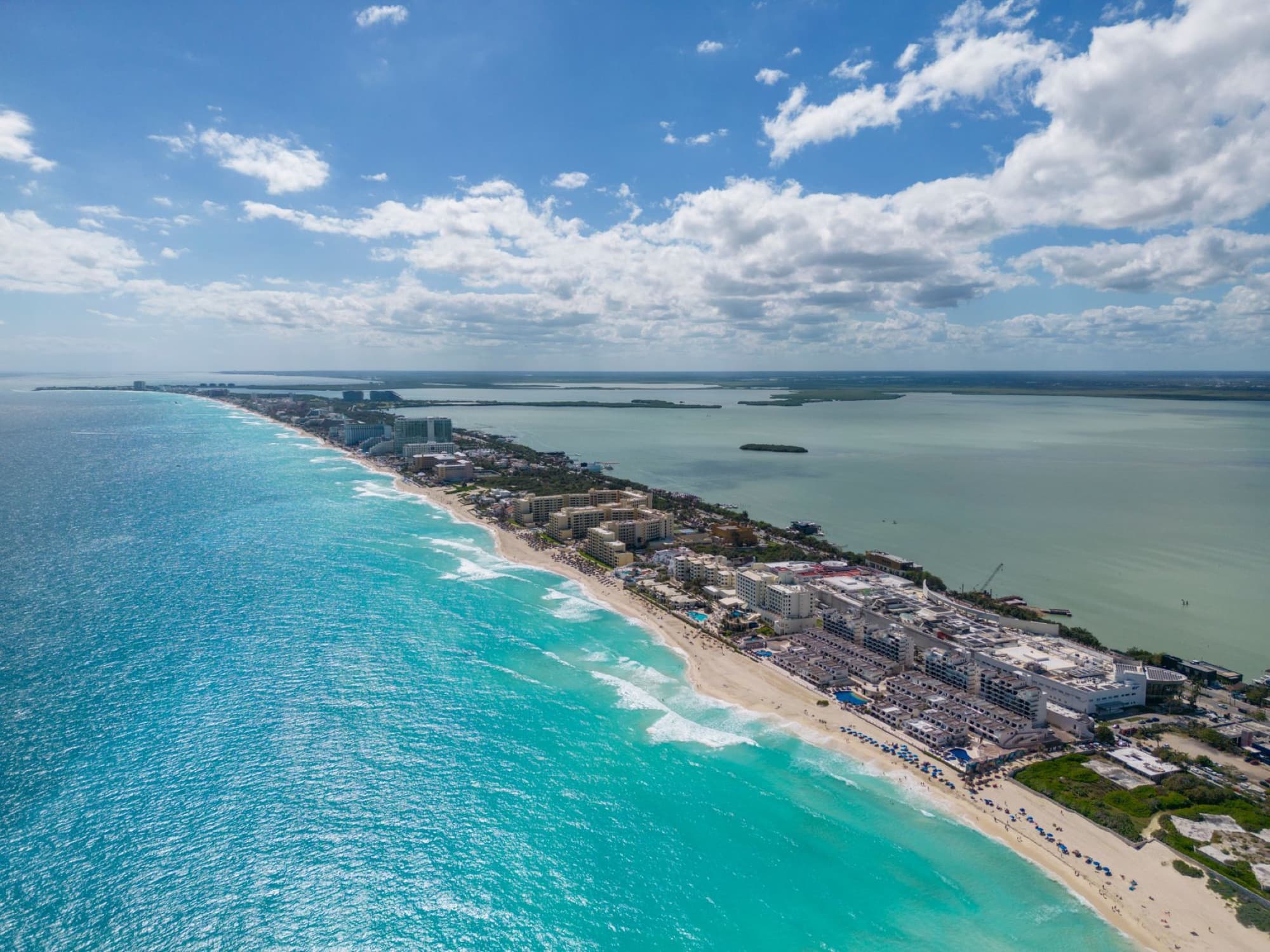 Stunning aerial view of Cancun's coastline with turquoise waters and city hotels under a clear sky.