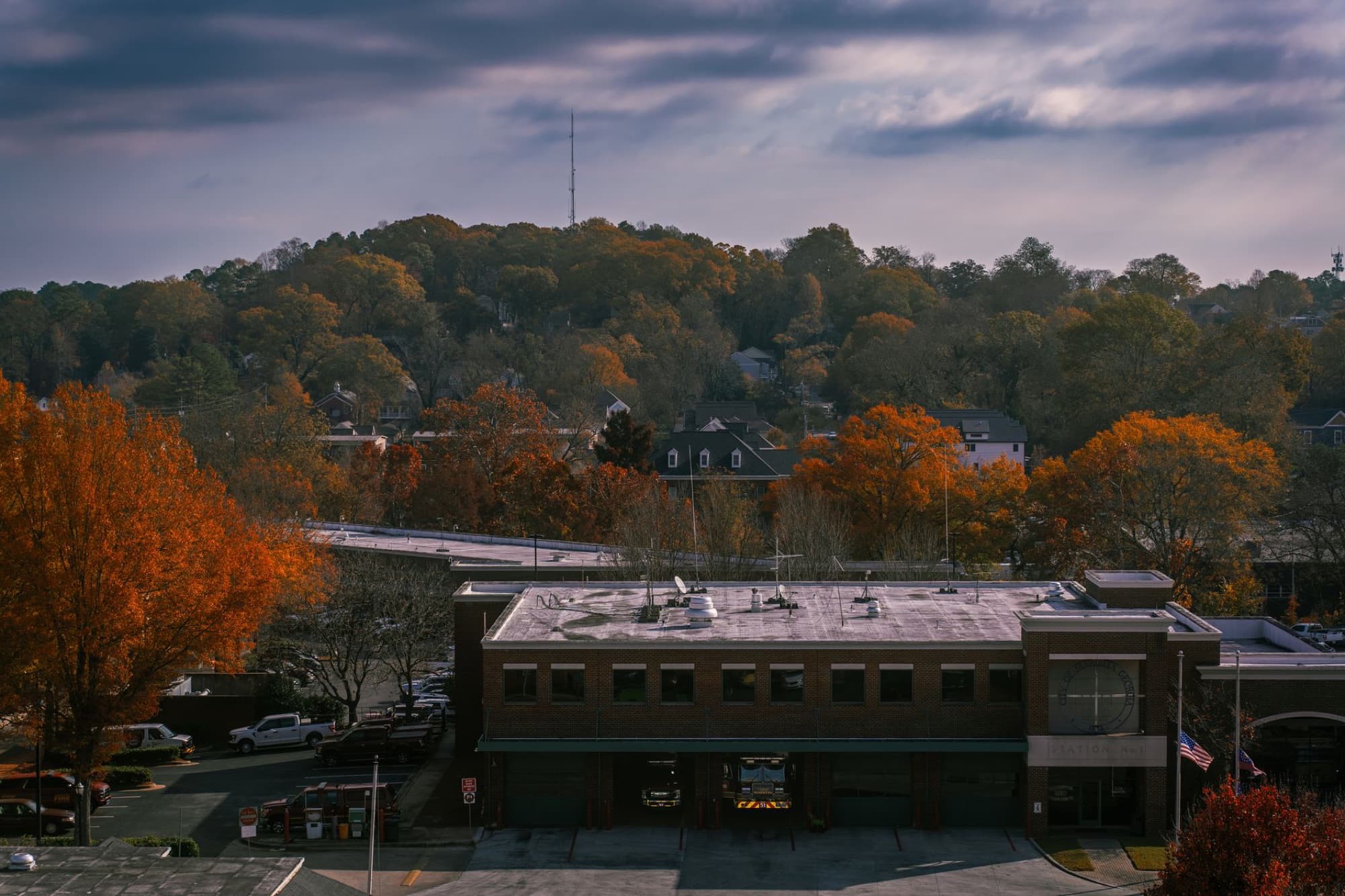 Scenic aerial view of a small town with vibrant autumn foliage and cloudy sky.