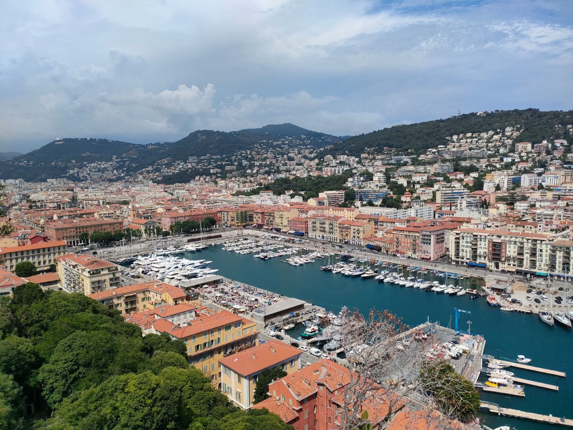Stunning aerial view of Nice harbor with colorful buildings and mountains in the background.