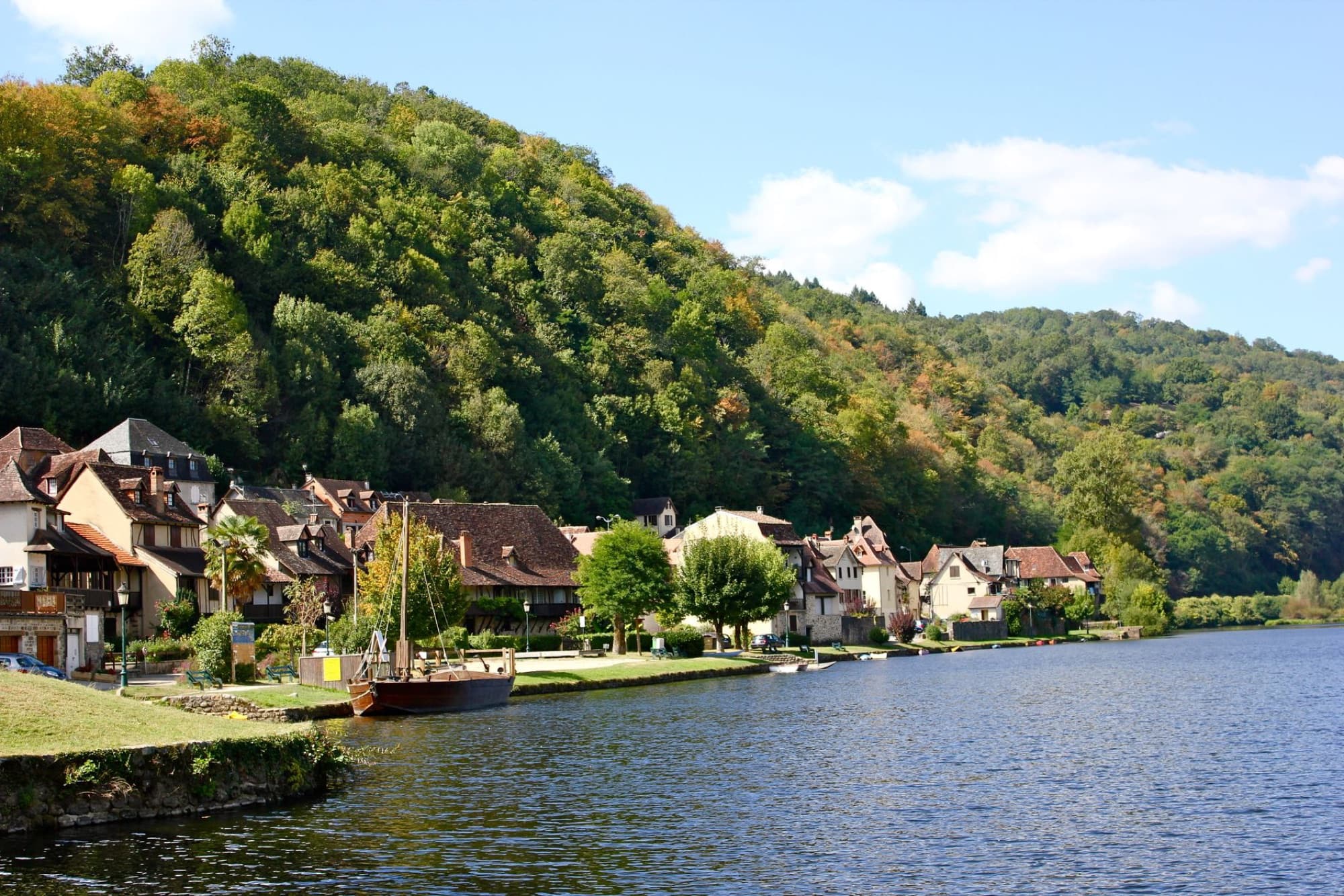 Charming riverside village of Beaulieu-sur-Dordogne, showcasing traditional French architecture along the Dordogne River in summer.