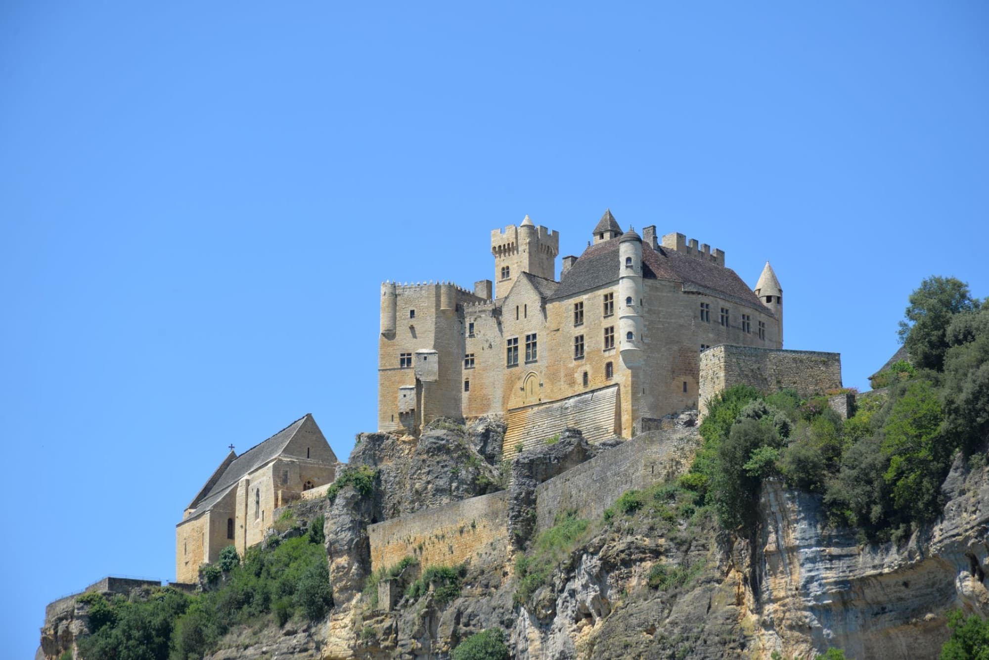 Majestic medieval Château de Beynac against a clear blue sky in Dordogne, France.