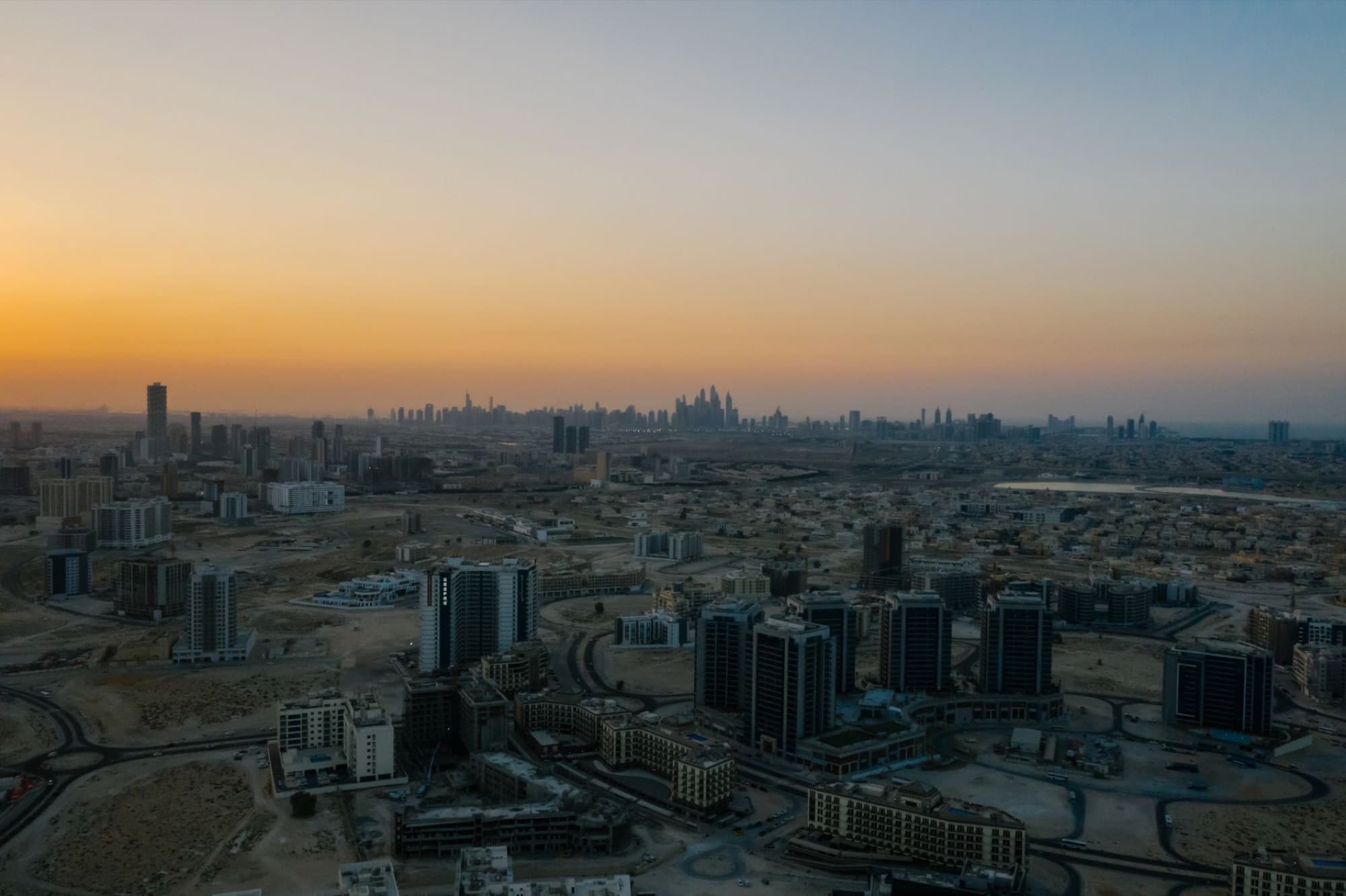 Stunning aerial view of Dubai cityscape at dawn with a warm skyline.