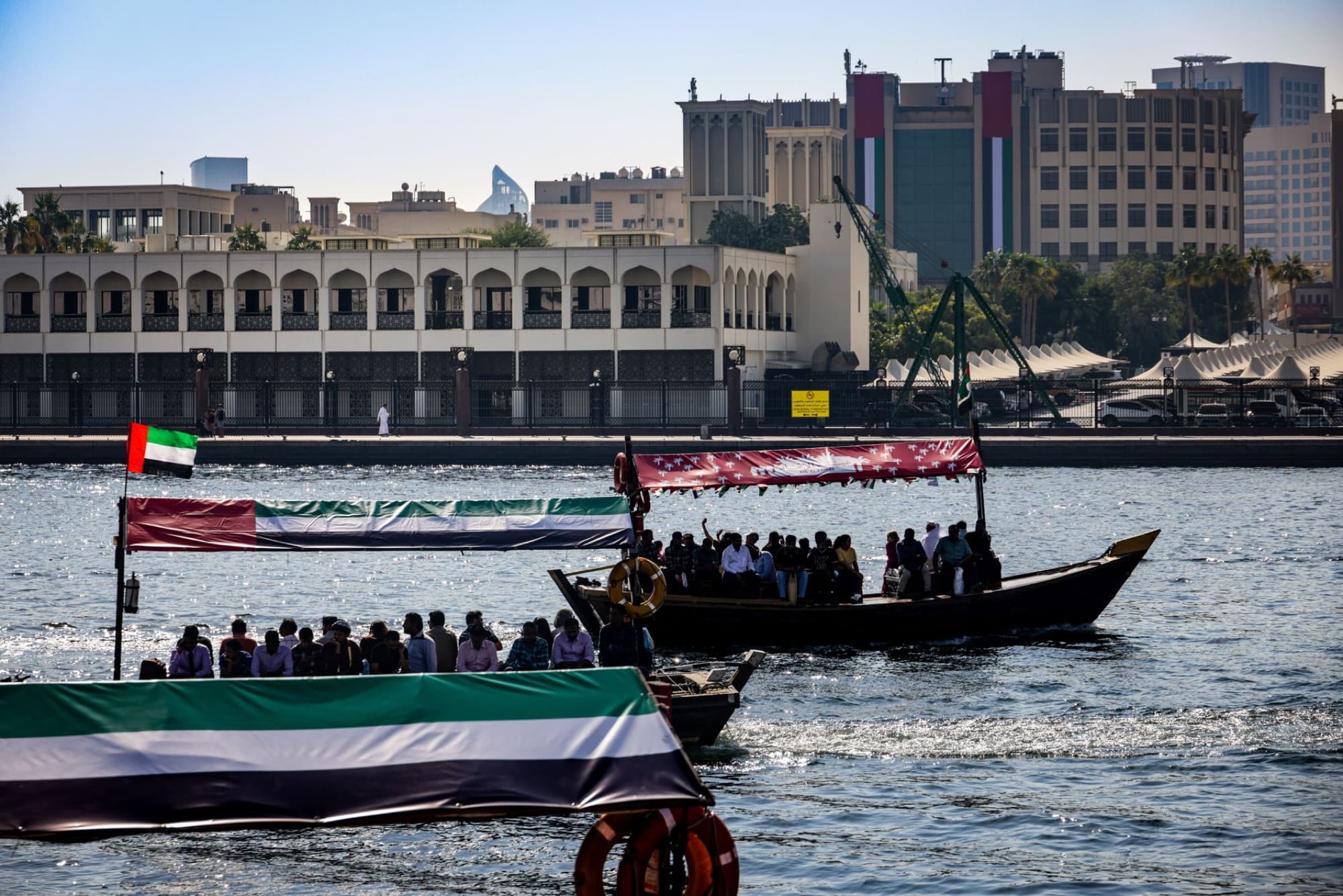 Traditional boats carry passengers on Dubai Creek with the city skyline backdrop.