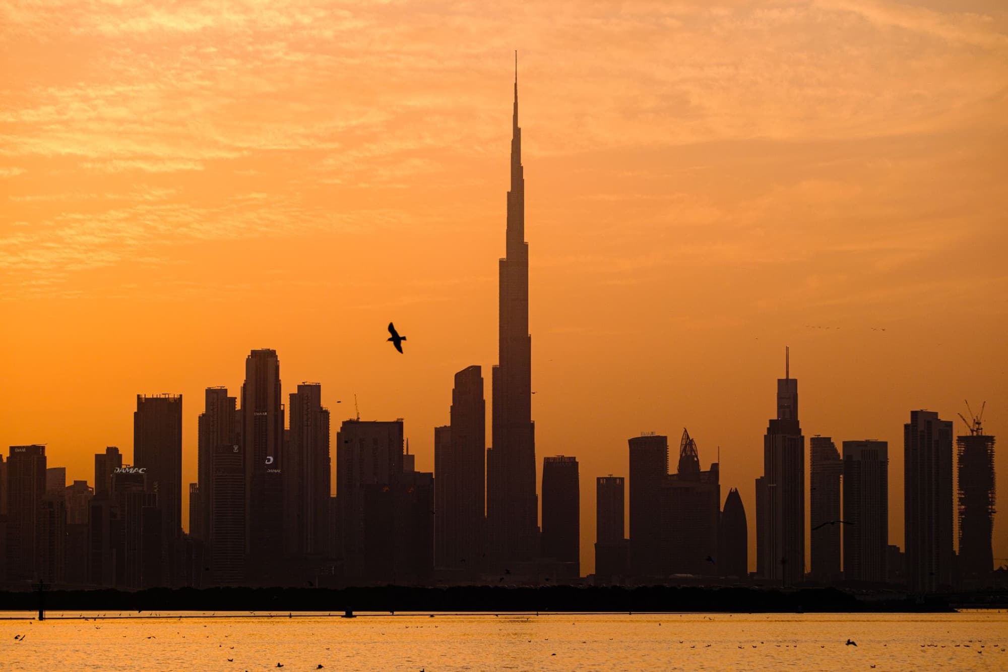 Dubai skyline silhouette with Burj Khalifa during a vibrant golden sunset.