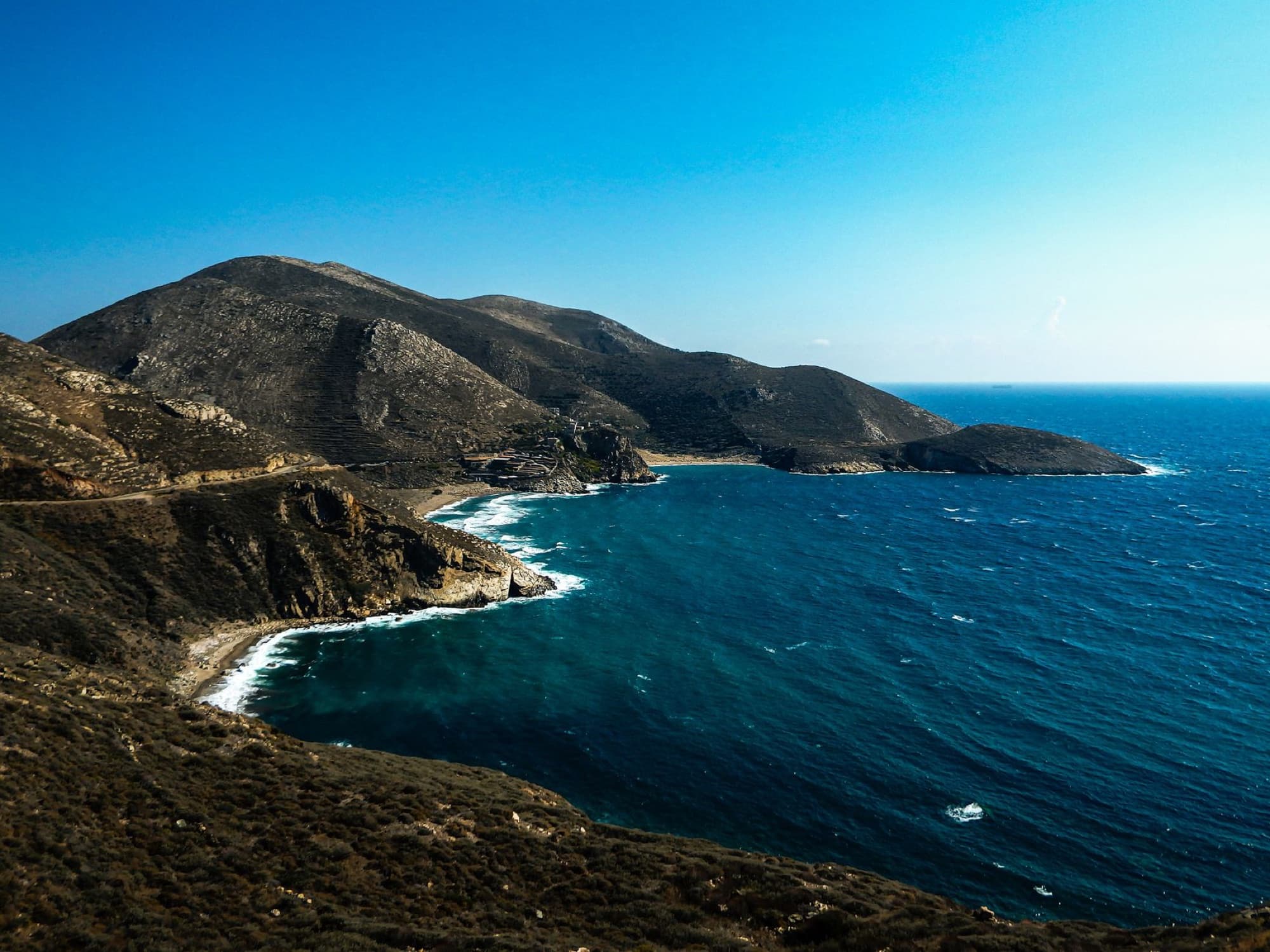 Stunning aerial photograph of the Peloponnesian coastline in Greece, showcasing vibrant blue waters and rugged cliffs.