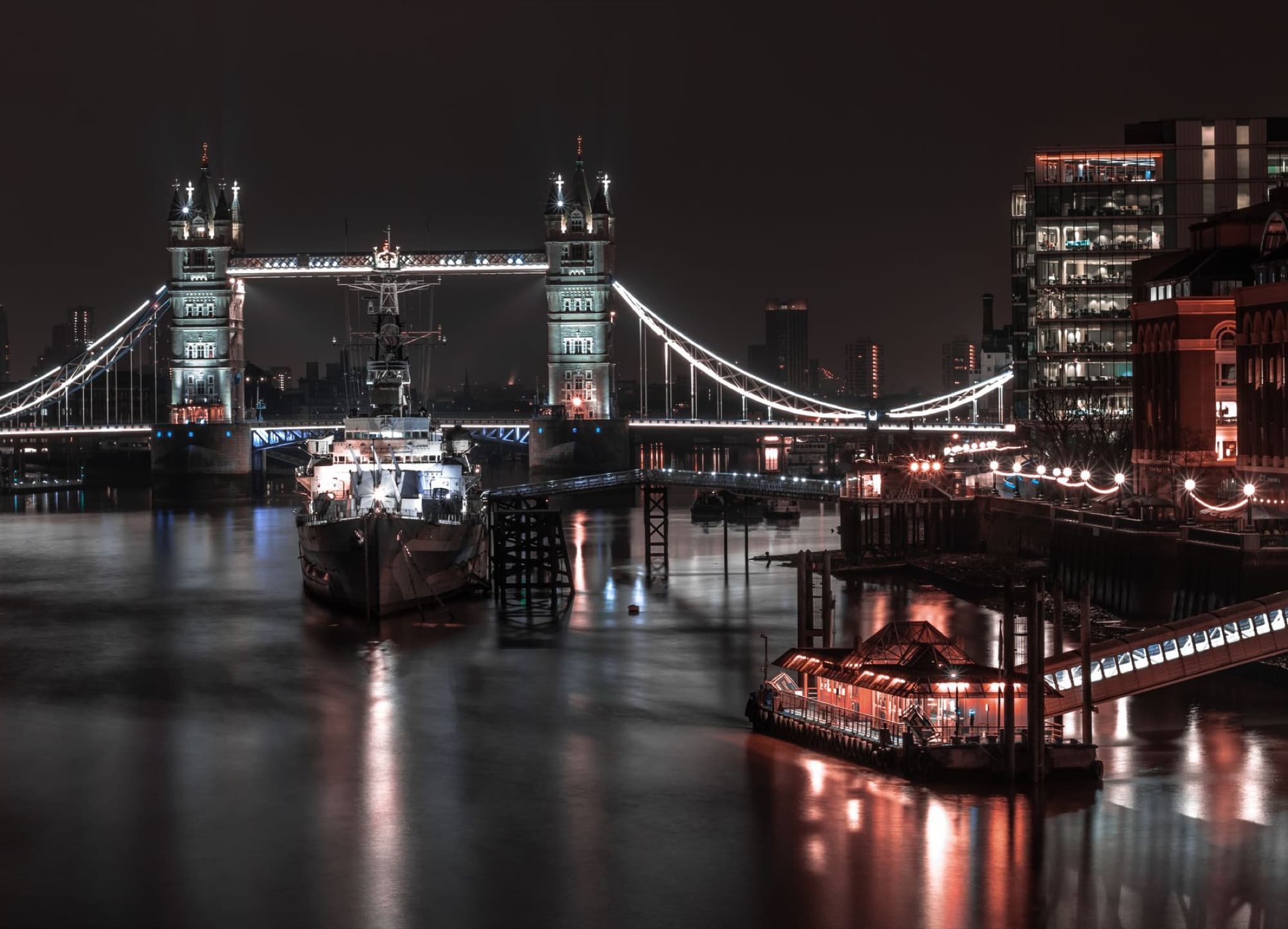 Illuminated Tower Bridge and Thames River at night in London, England.