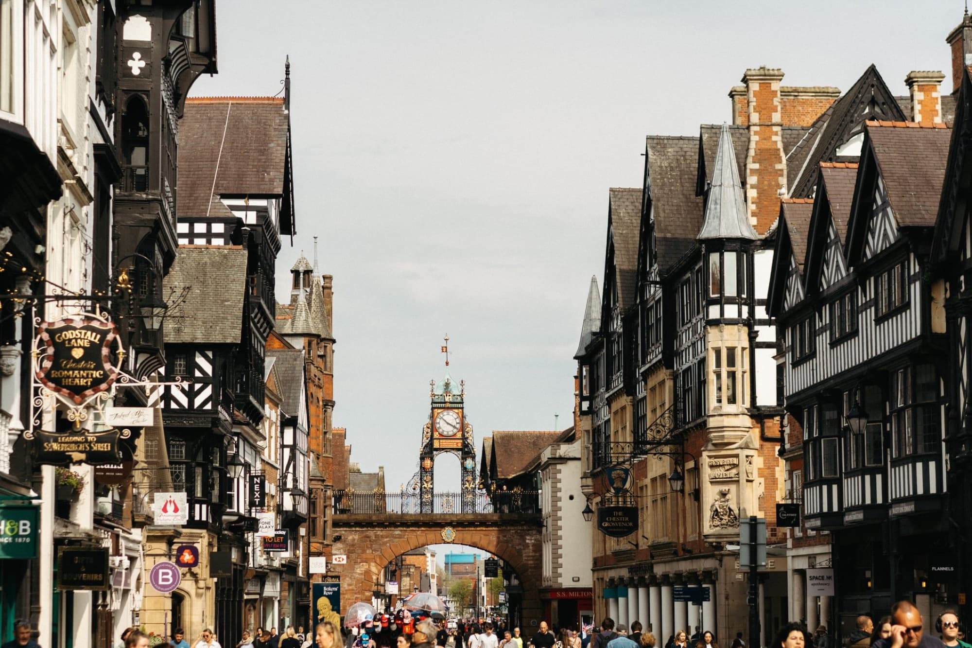 Busy street in Chester, England, featuring medieval architecture and the iconic Eastgate Clock.