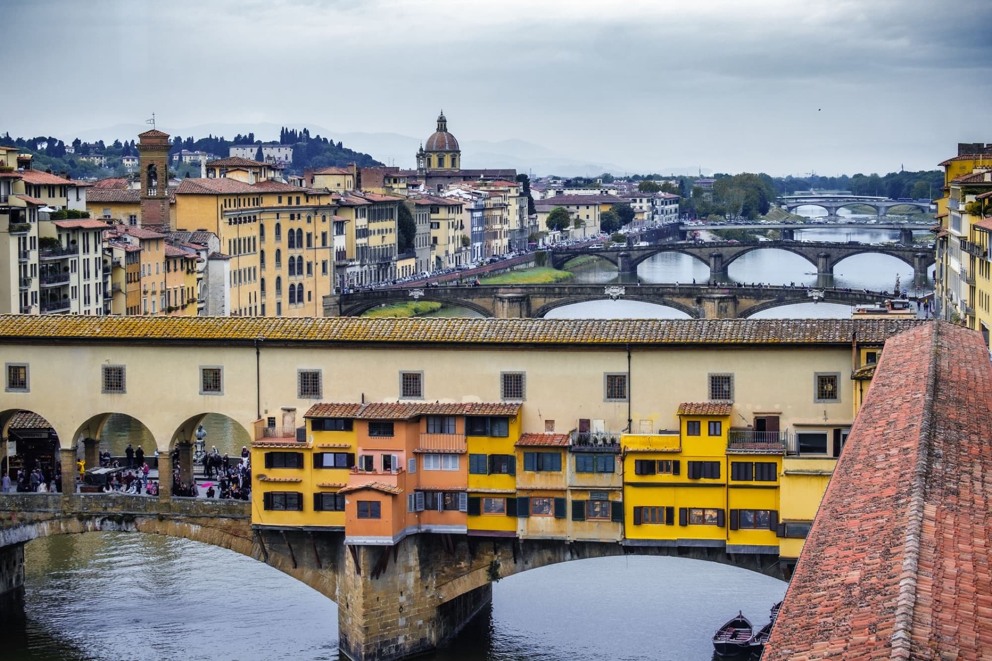 Stunning view of Florence's historic Ponte Vecchio spanning the Arno river with city skyline.