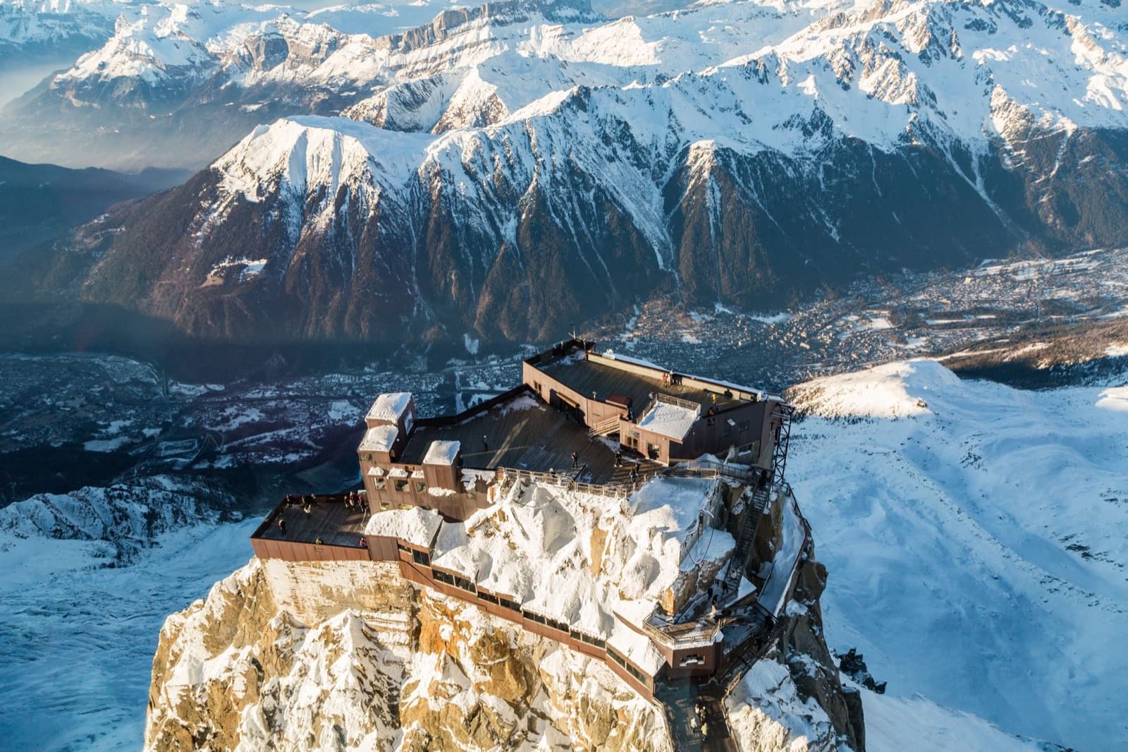Majestic aerial view of snow-covered mountain peaks and a scenic observation deck during winter.