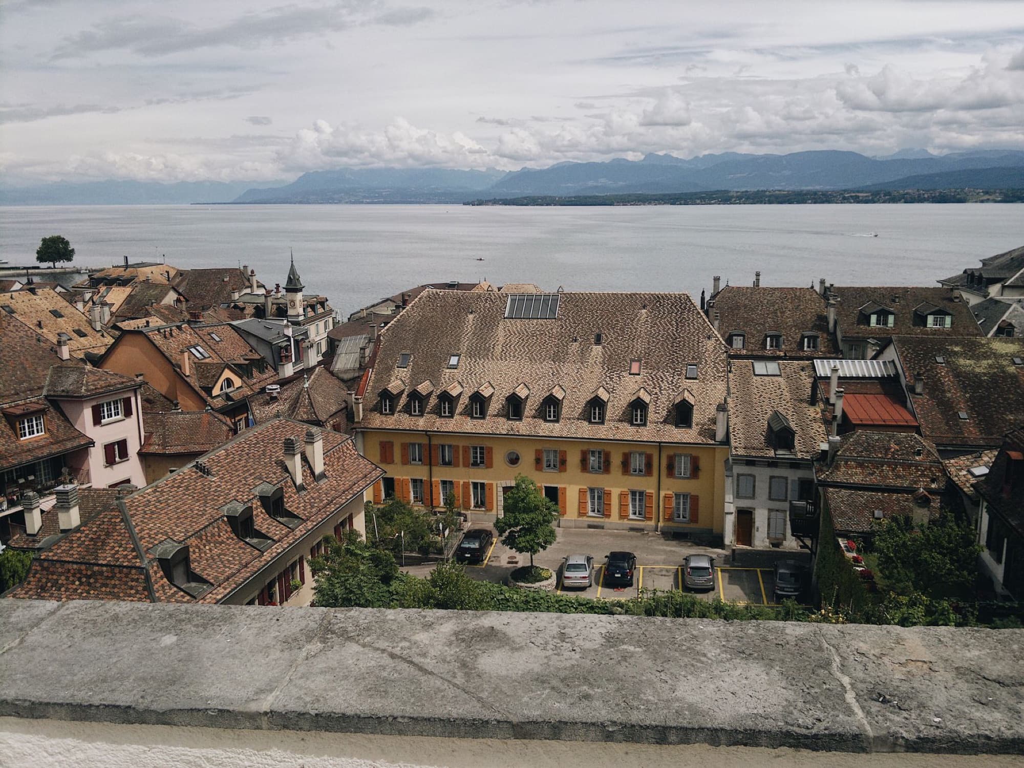 A scenic aerial view of Geneva's classic architecture with Lake Geneva and mountains.