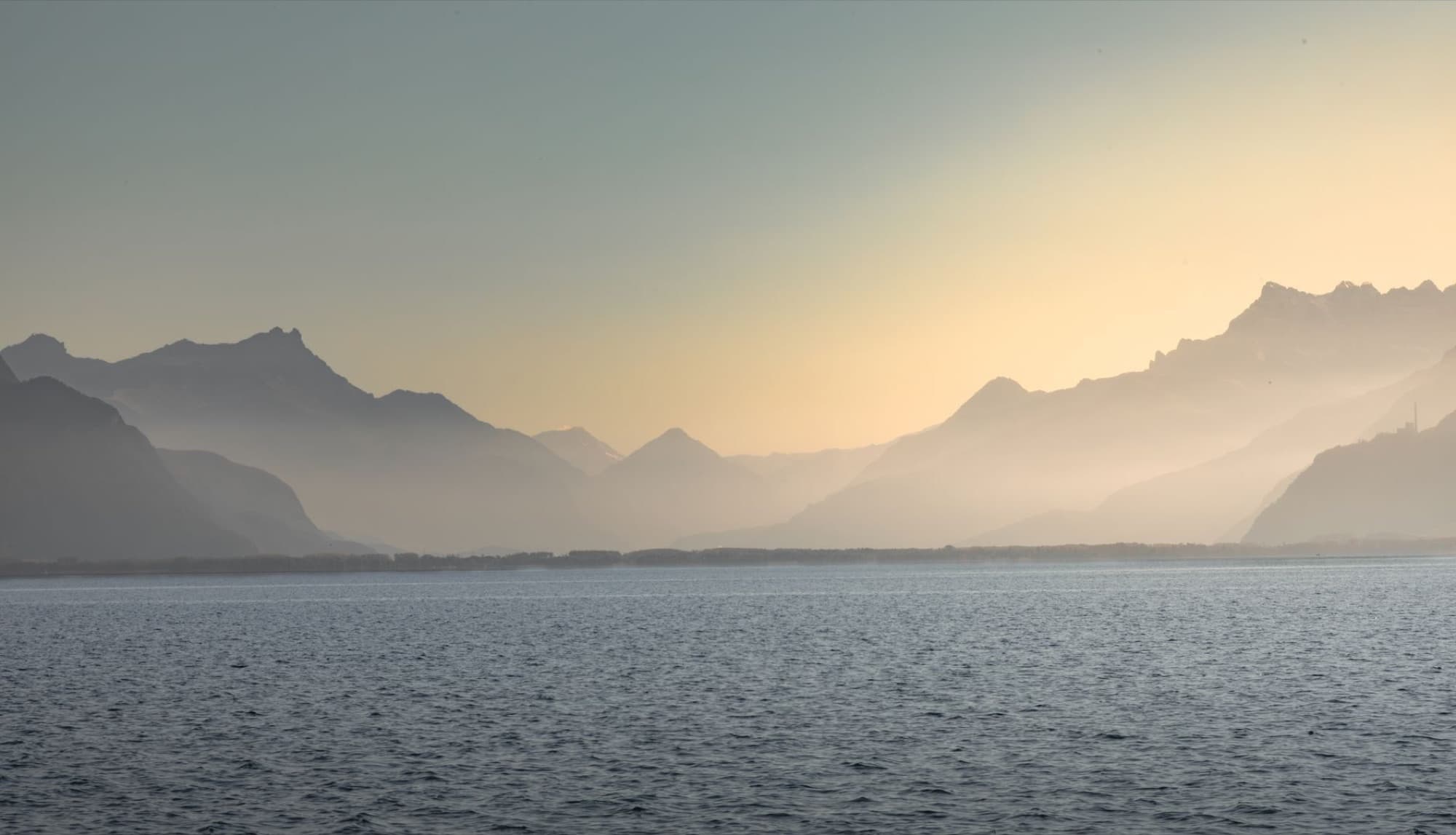 Peaceful view of misty mountains and Lake Geneva at sunset in Vevey, Switzerland.
