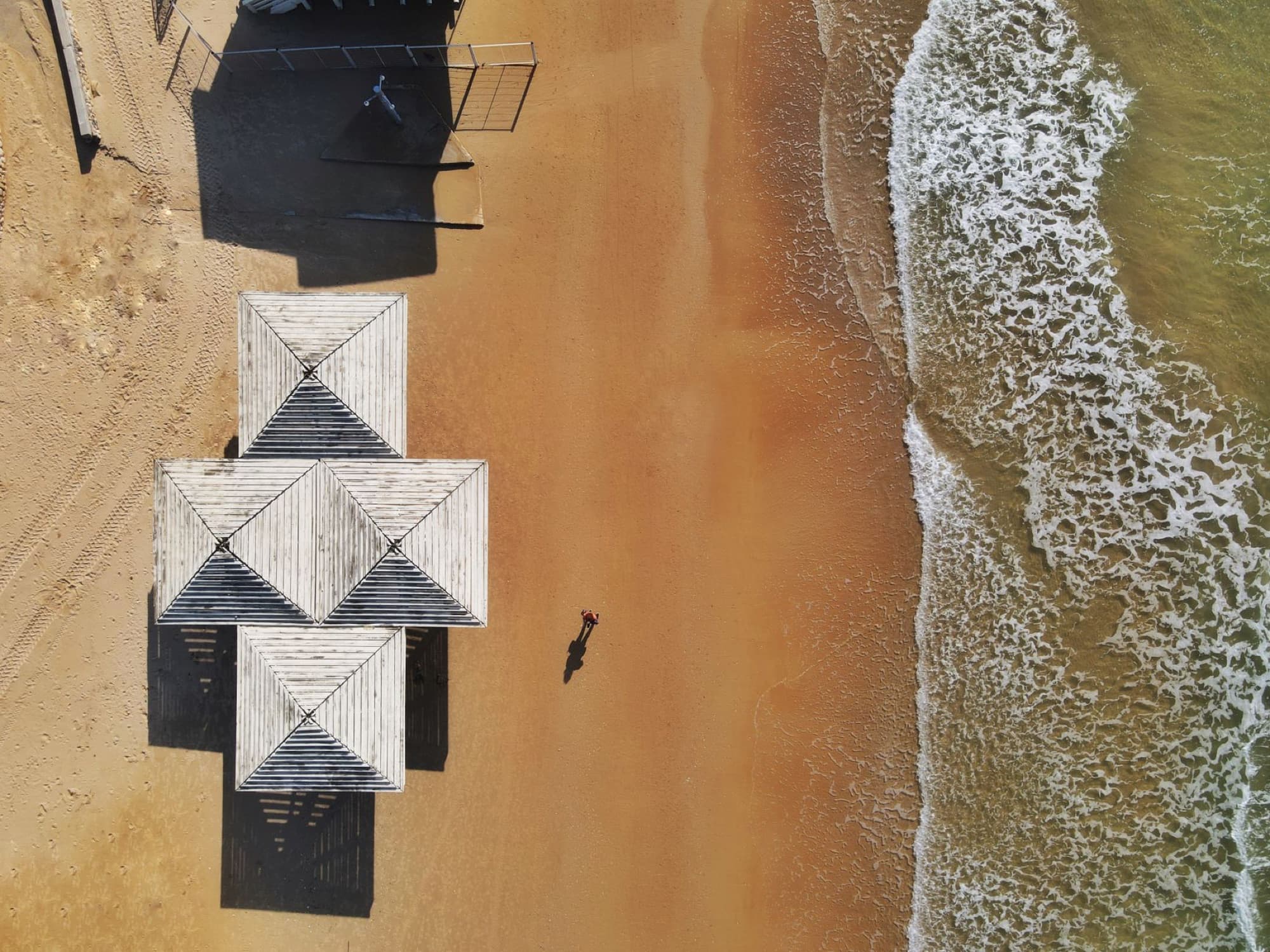A stunning aerial view of sandy beach and white structures next to waves in Haifa, Israel.