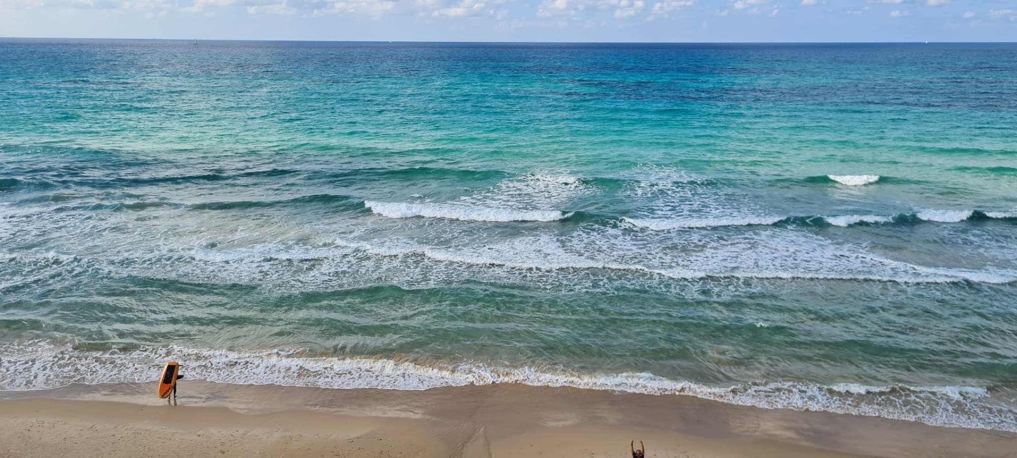 Aerial view of waves crashing on Herzliya beach in Israel, showcasing serene coastal scenery.