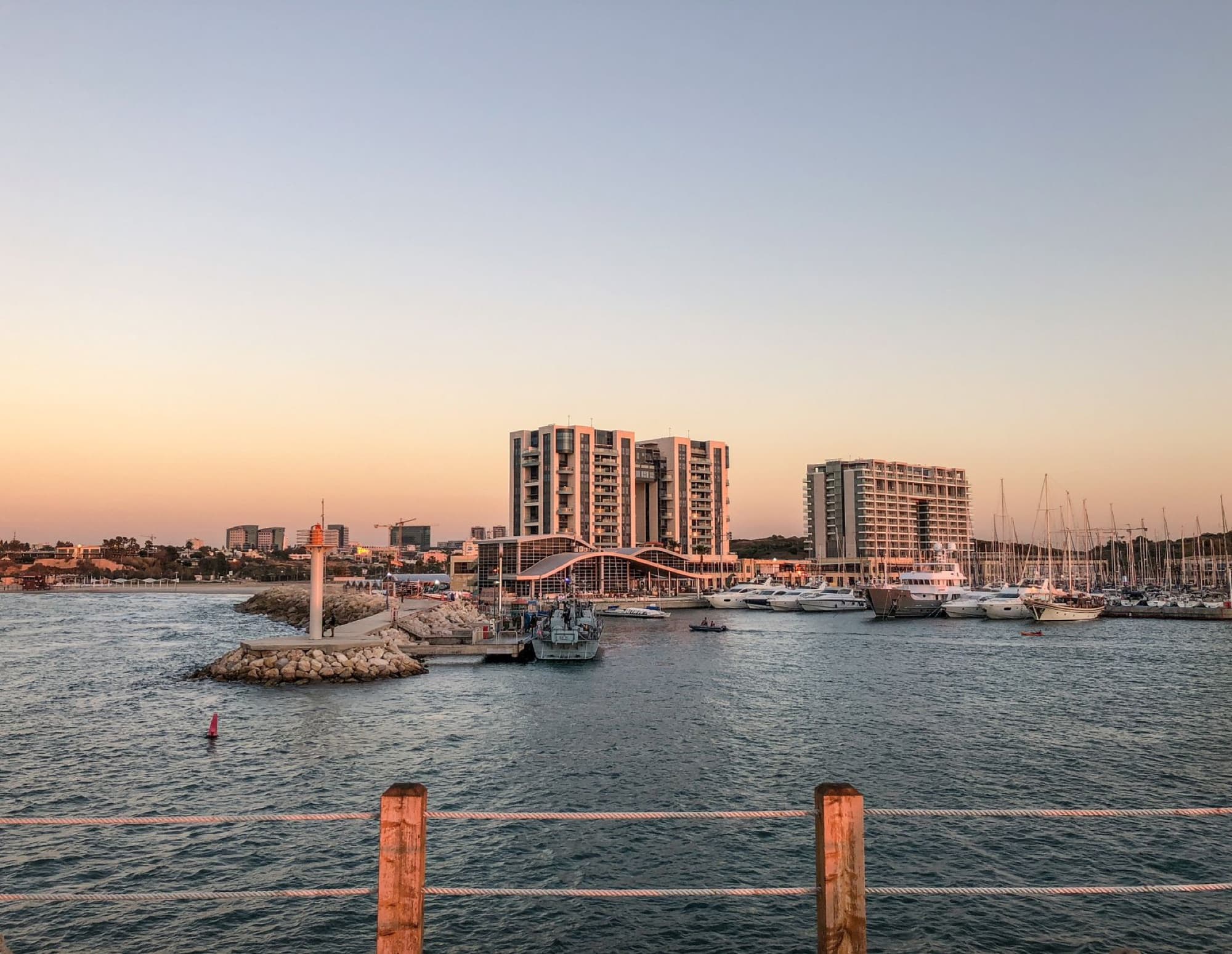 Explore the picturesque Herzliya Marina in Israel with yachts and modern architecture at sunset.