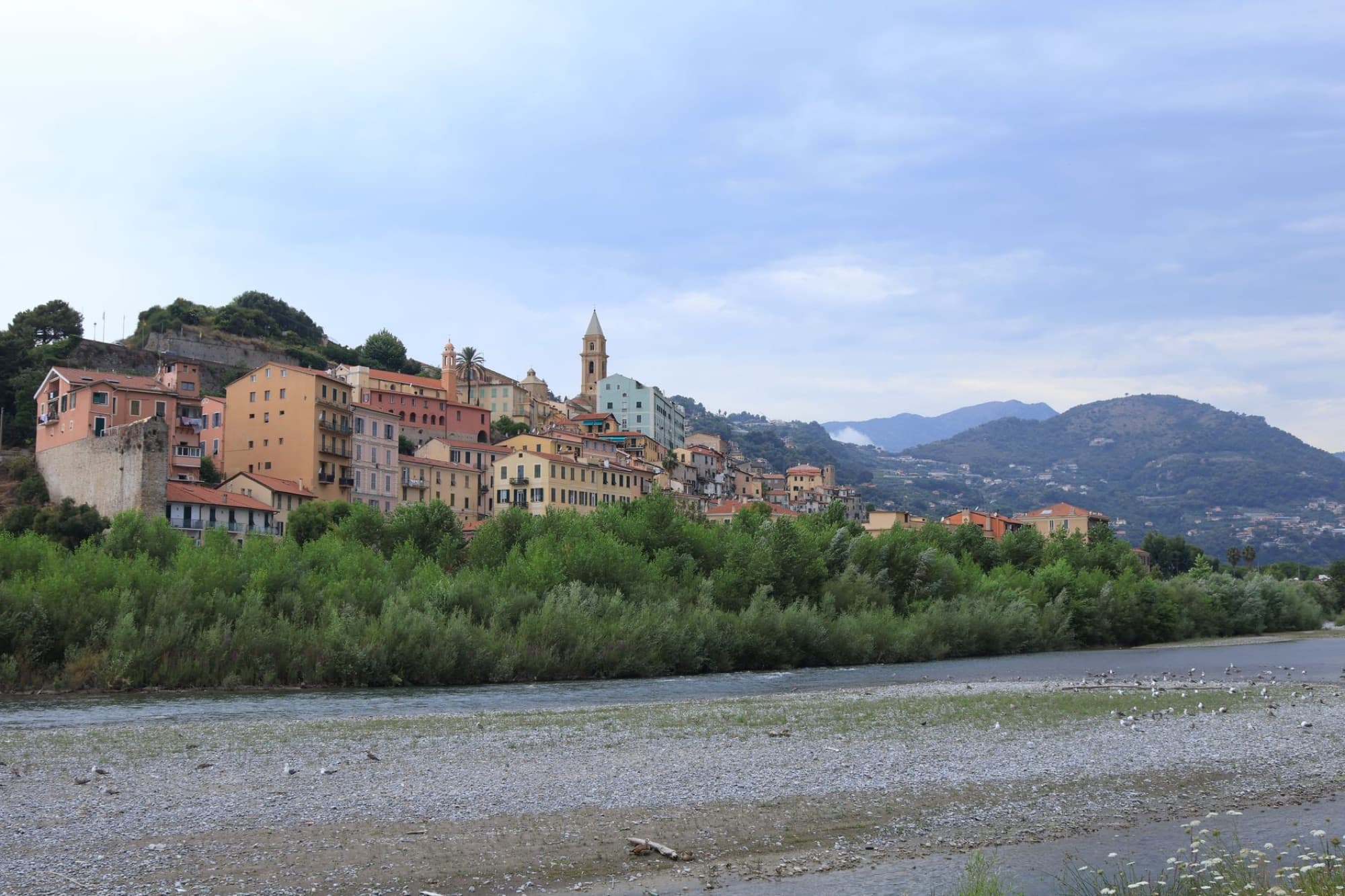 Picturesque hillside town on the Italian Riviera with colorful buildings under a cloudy sky.