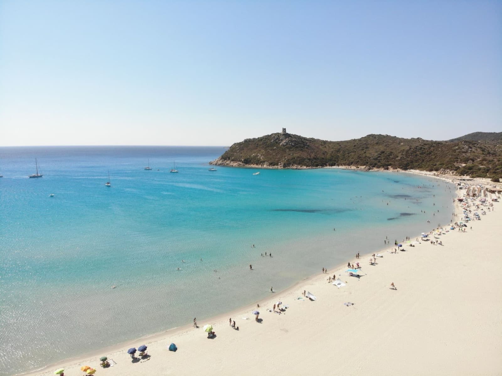 Drone shot capturing the vibrant turquoise waters and pristine beaches of Sardegna, Italy, full of life.