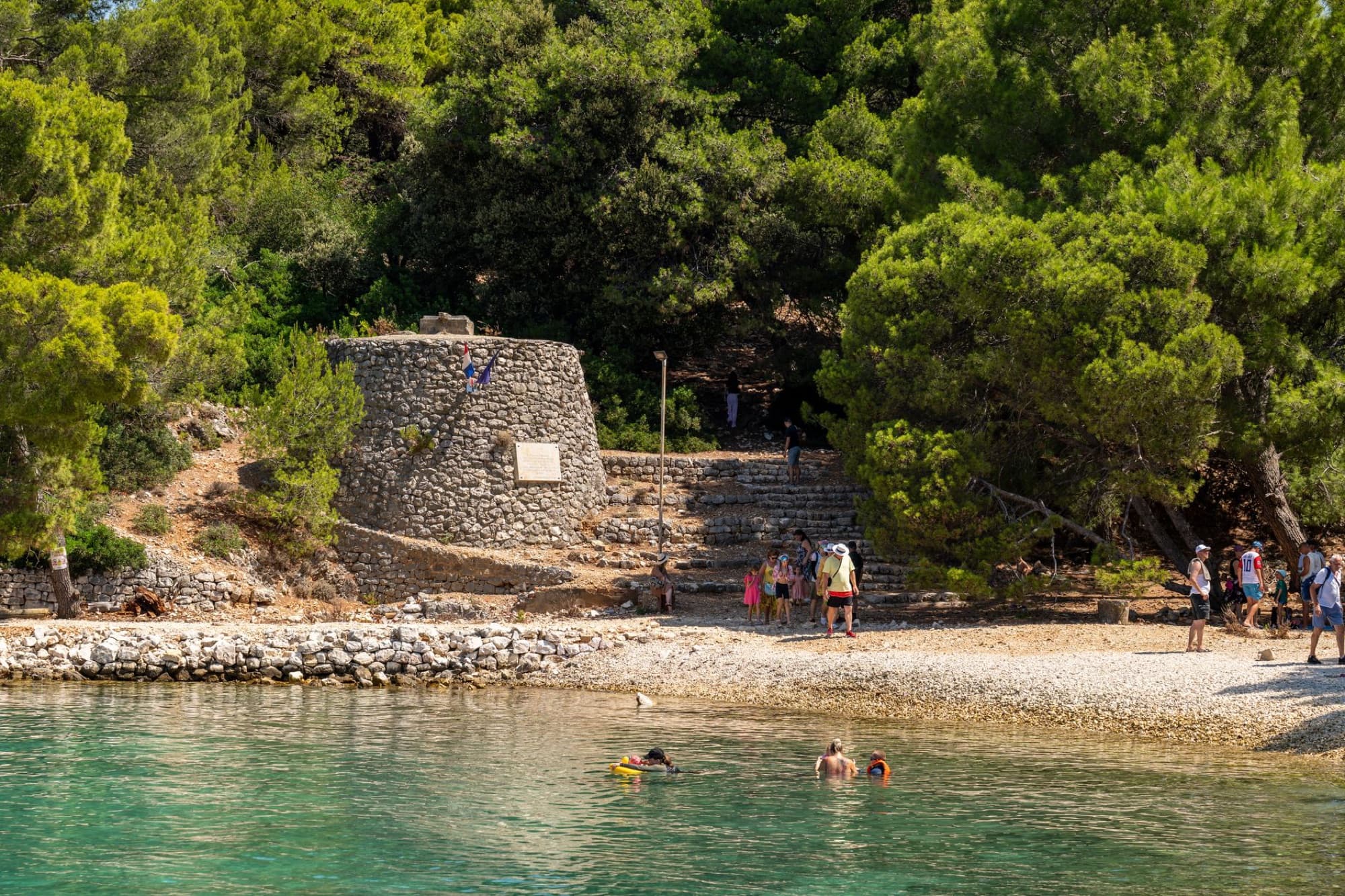 Tourists enjoy a sunny day by the rocky beach in Kvarner Bay, Croatia.