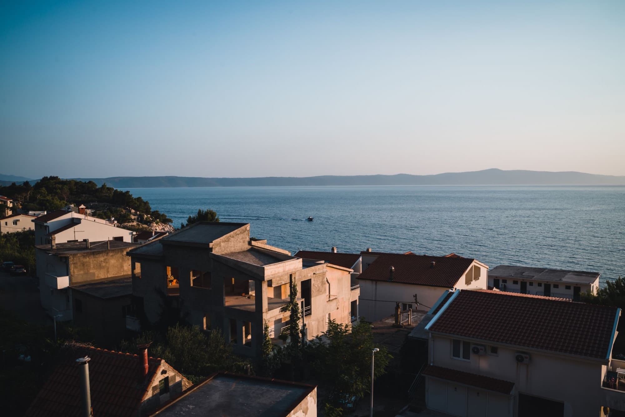 Scenic view of a Mediterranean village overlooking the sea at sunset.