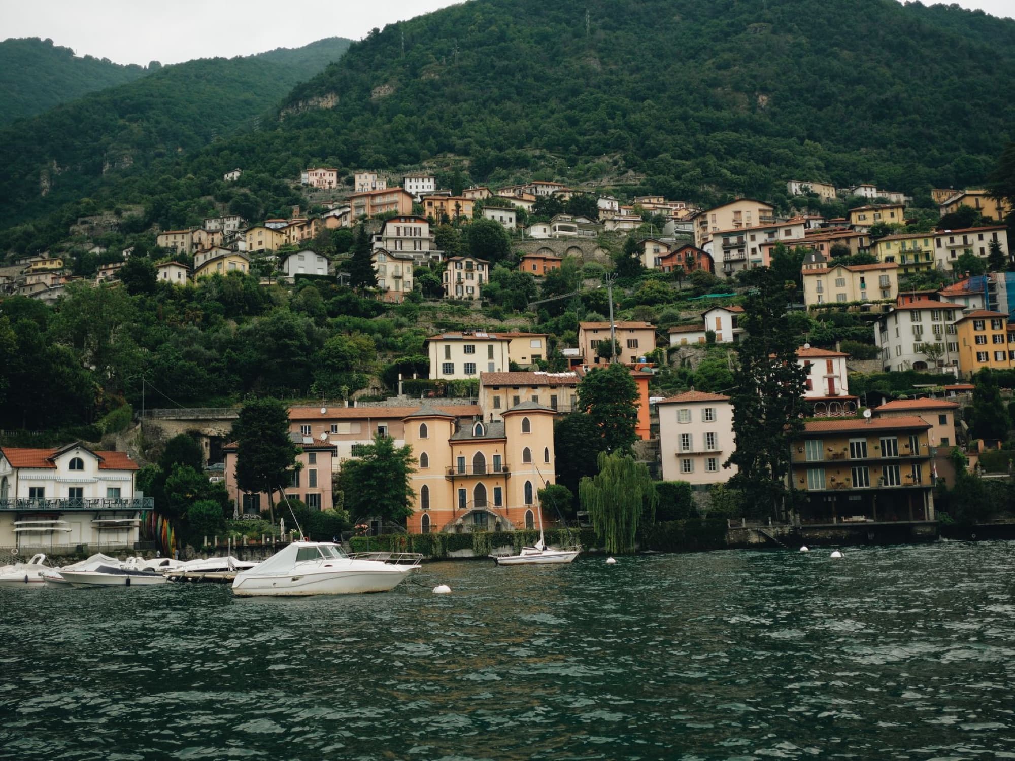 Scenic view of charming village by Lake Como in Lombardy, Italy. Boats docked at the waterfront.