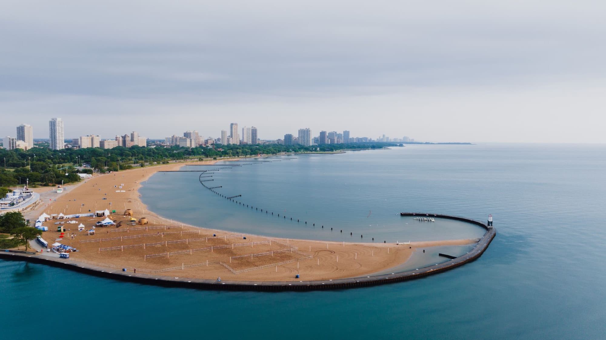 Scenic aerial view of Chicago's coastline with sandy beach and urban skyline under a cloudy sky.
