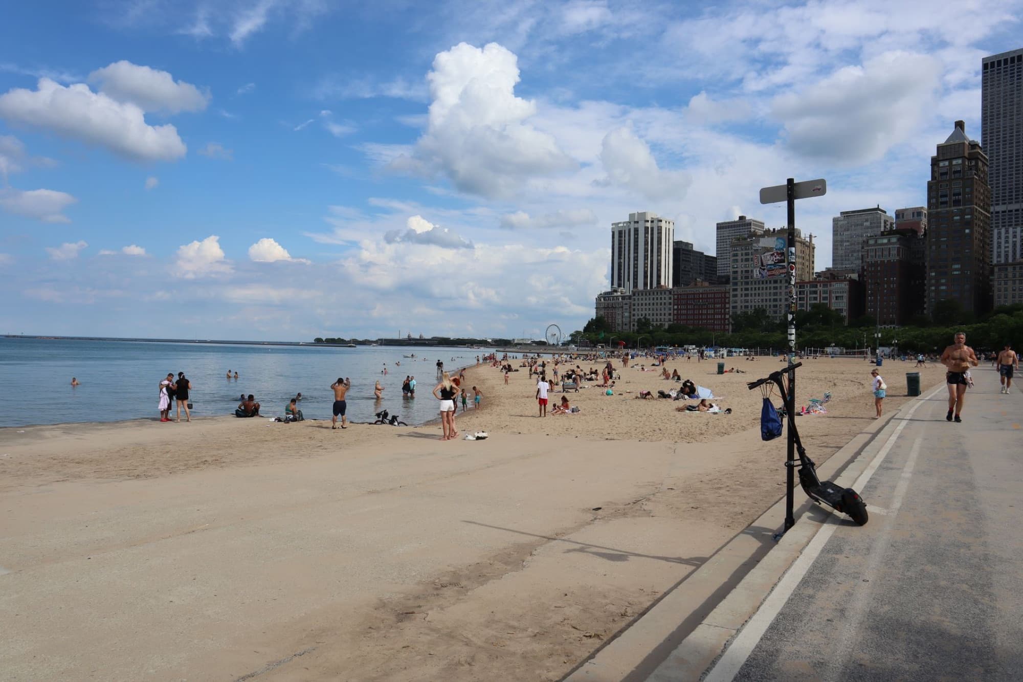 View of Chicago city skyline from a busy lakeshore beach on a sunny summer day.