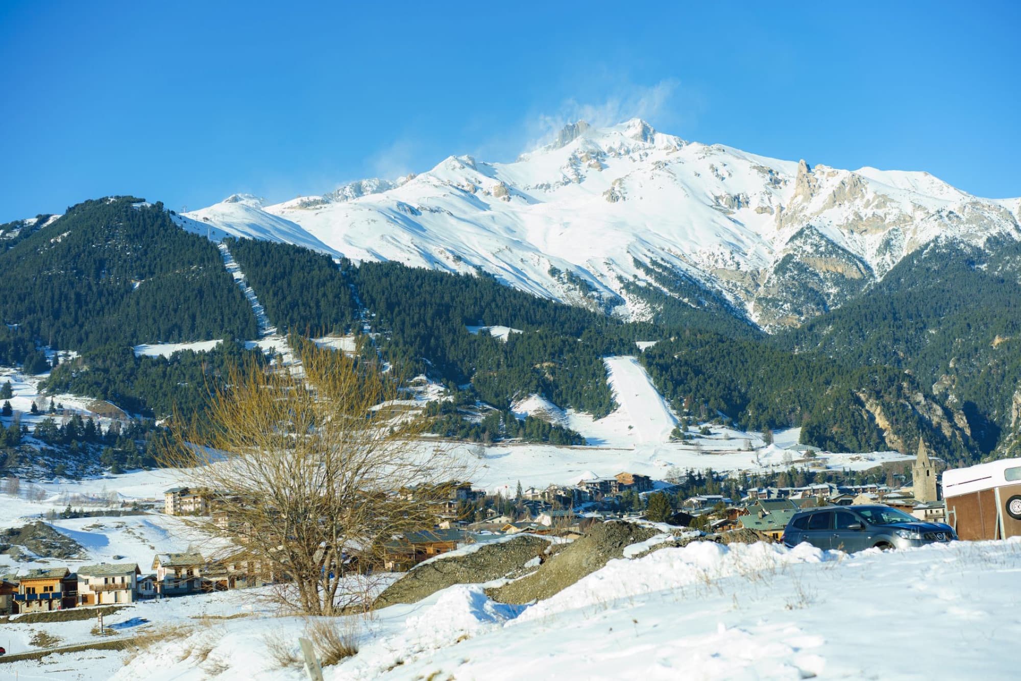 Scenic view of a snowy village nestled by mountains showcasing winter beauty.