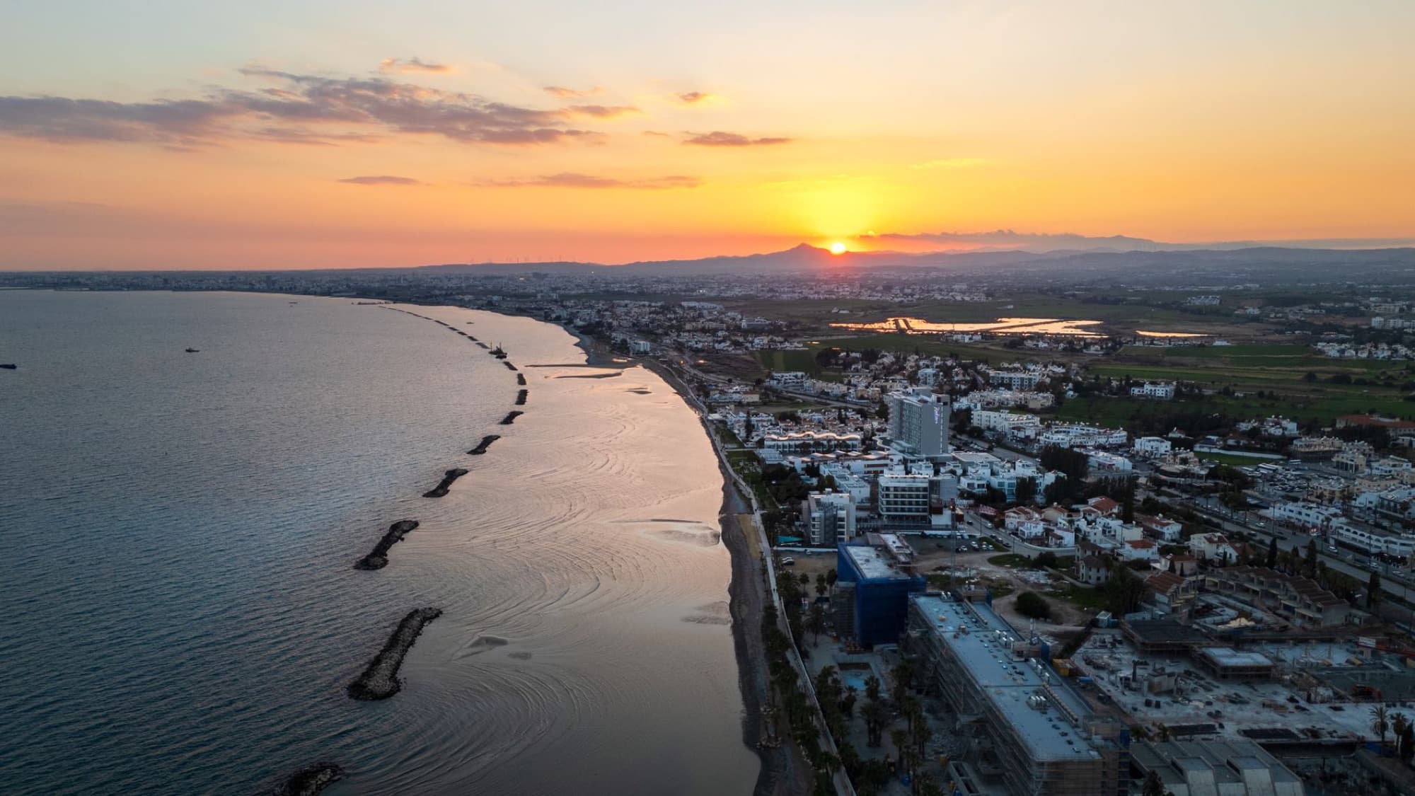Aerial view of Limassol's coastline during sunset, showcasing the vibrant city and serene sea.