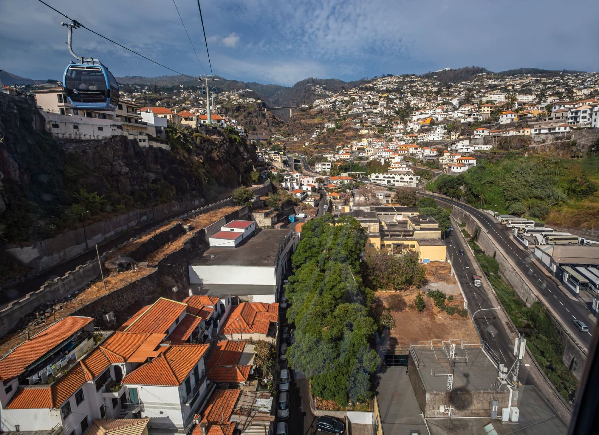 Aerial shot of Madeira Island showcasing town, cliffs, and cable car.