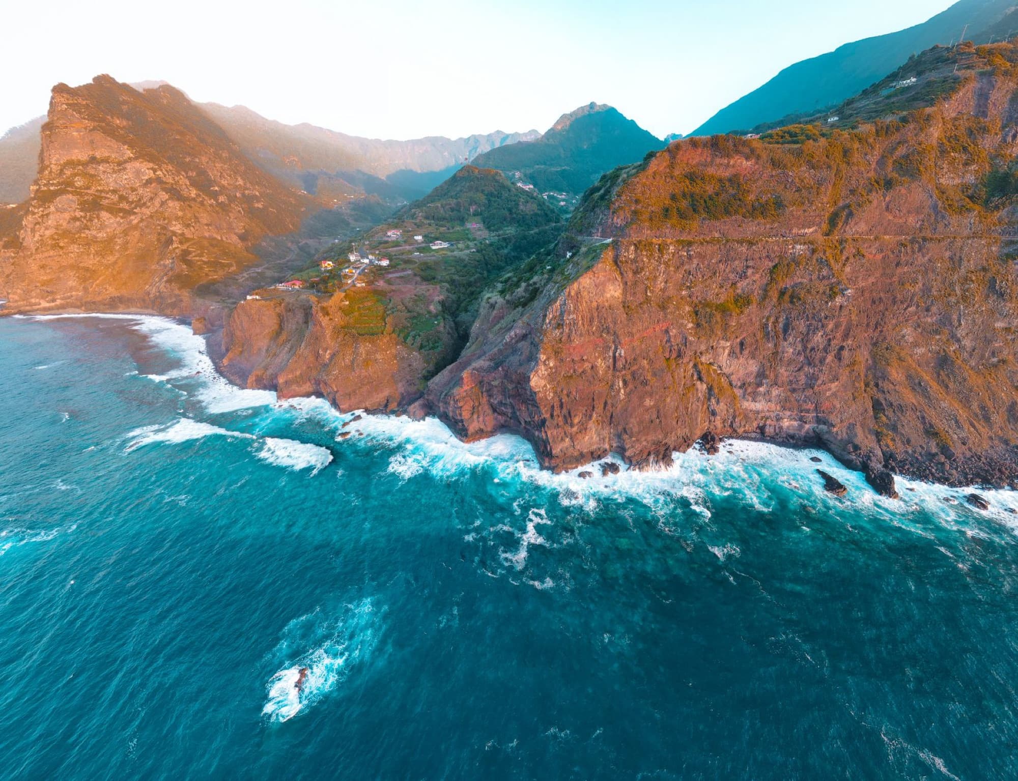 A stunning aerial view of the rocky coastline and cliffs of Madeira, Portugal during the day.