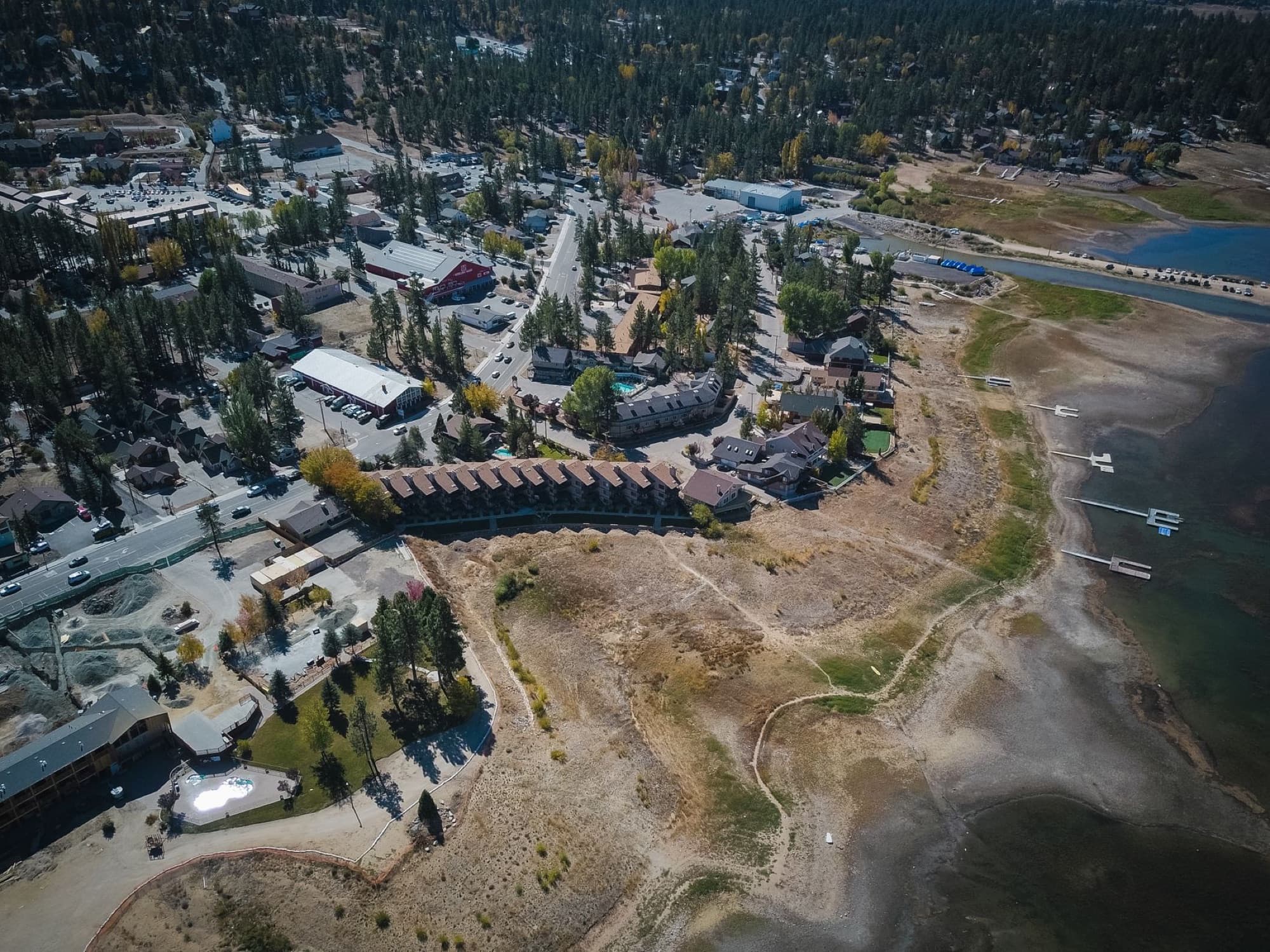 Explore a scenic aerial view of a picturesque lakeside town surrounded by lush forests and blue waters.