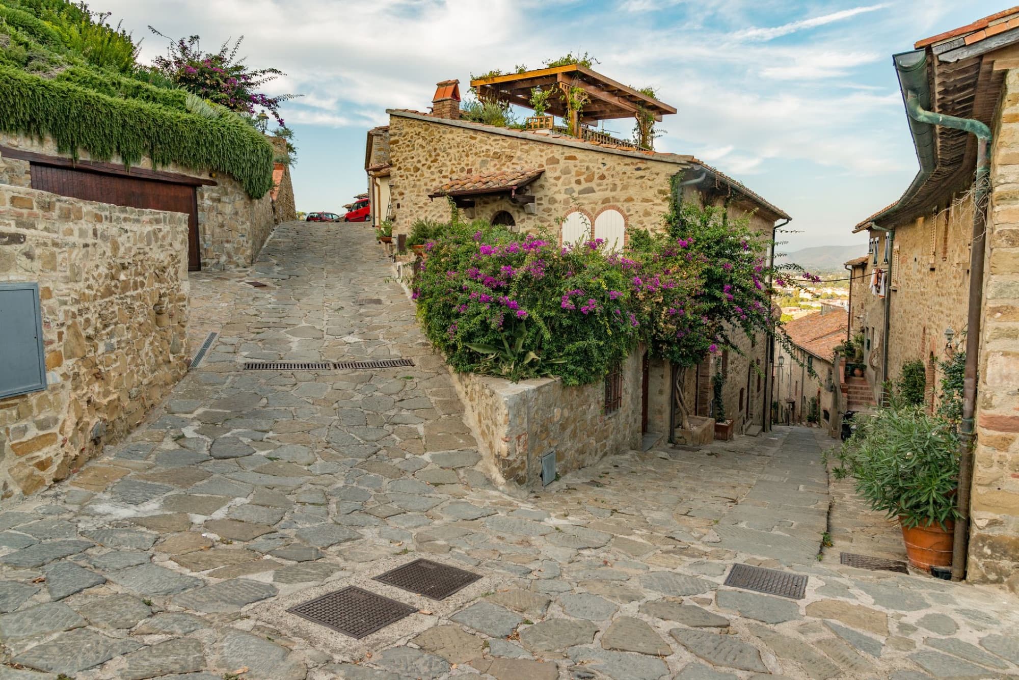 Picturesque stone street with historic houses and vibrant flowers in a charming old town setting.