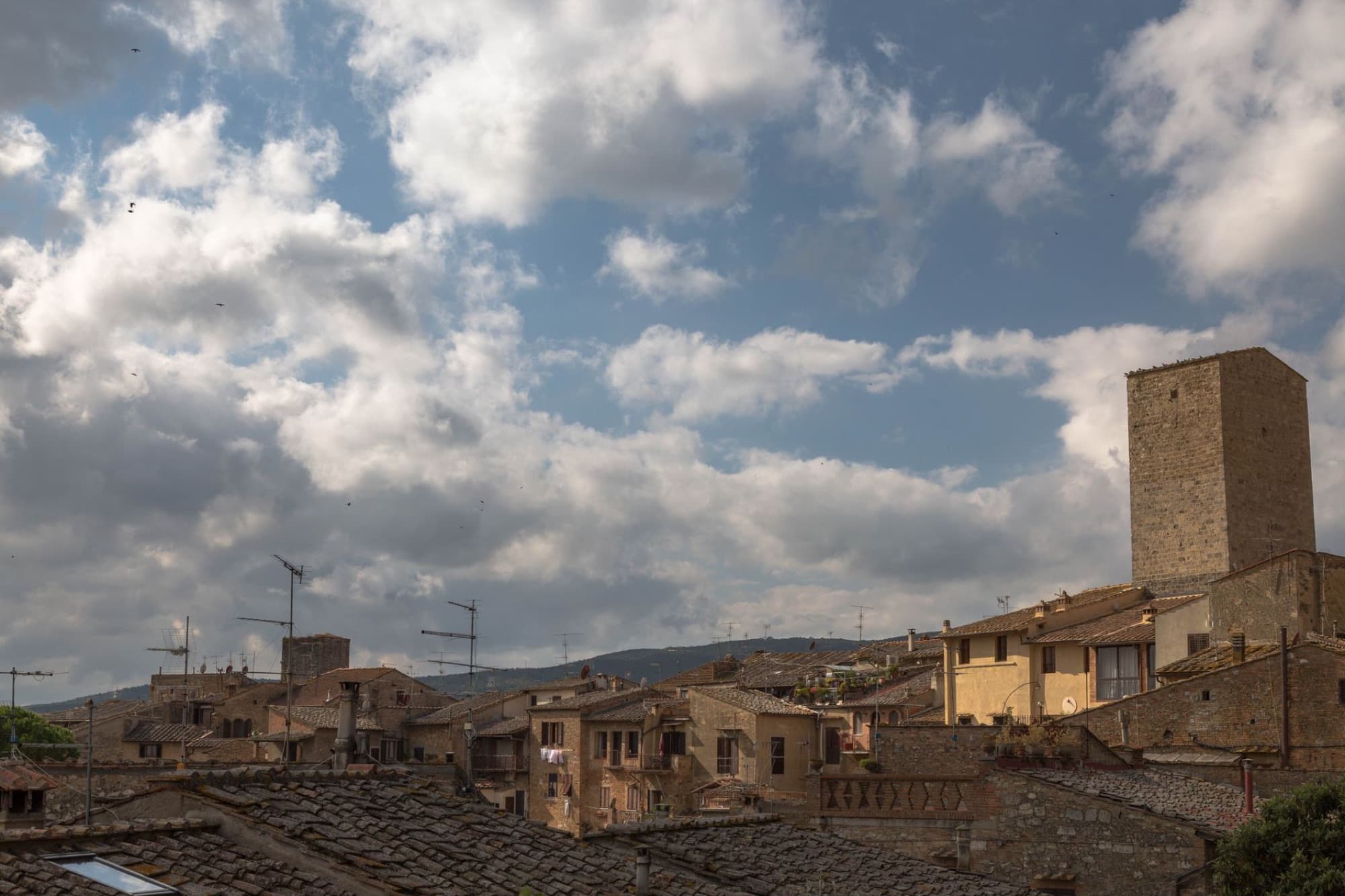 A scenic view of historic rooftop architecture beneath a dramatic cloudy sky.