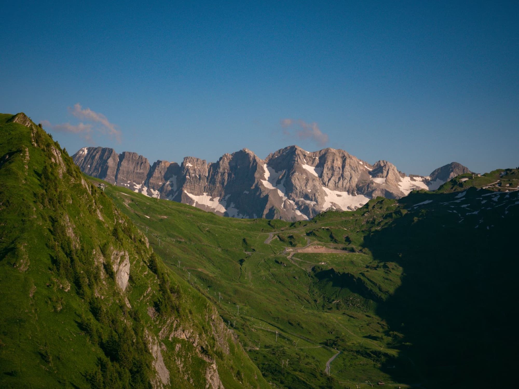 Scenic view of lush green valleys and snow-capped peaks in Morzine, France.