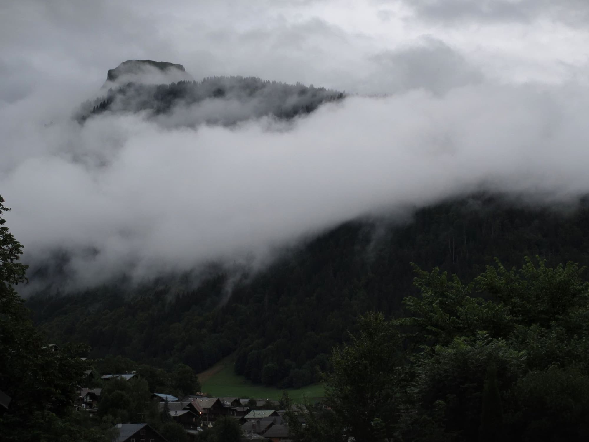 Misty view of Morzine village nestled in the foggy French Alps during a cloudy day.