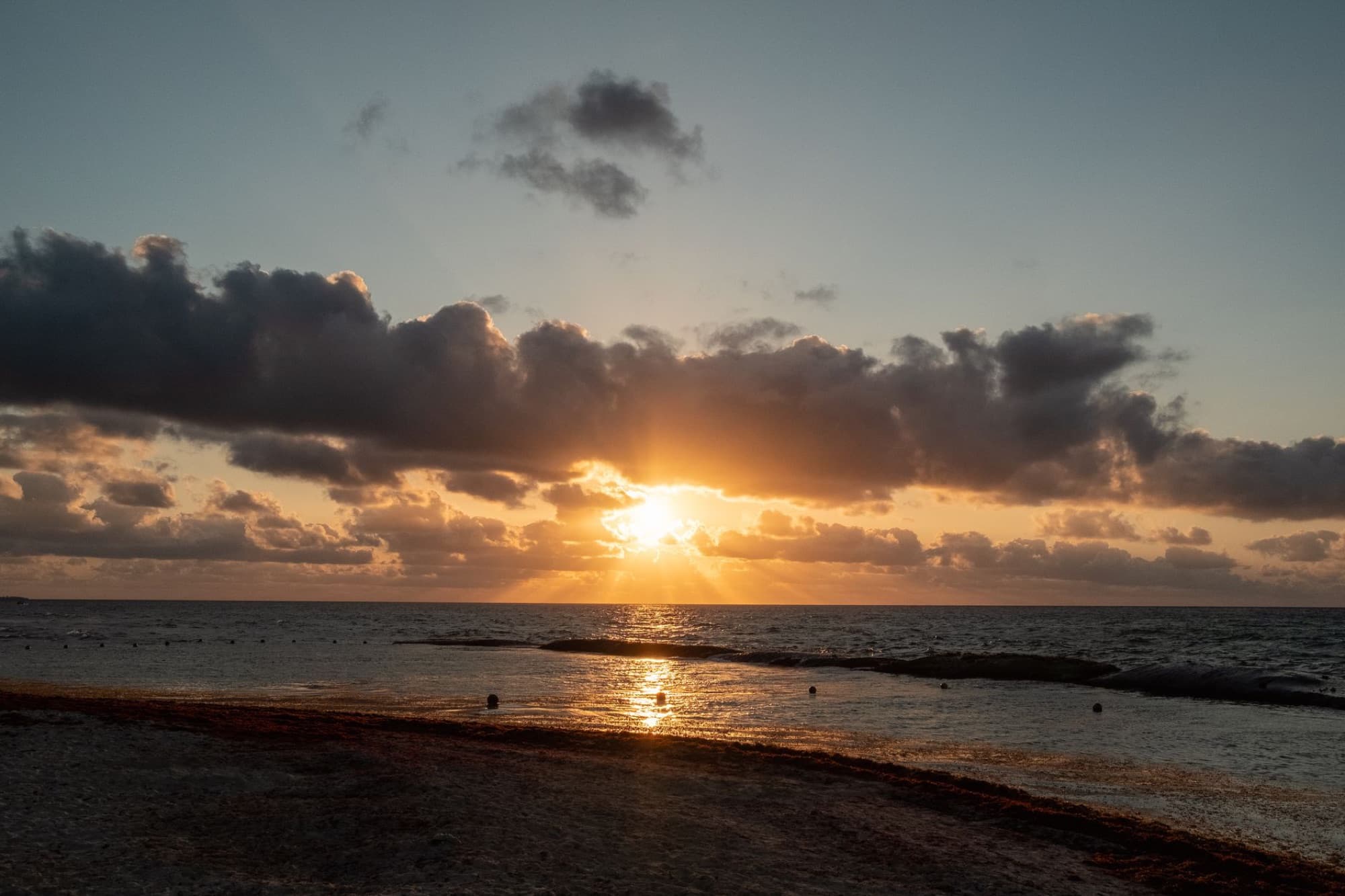 Serene sunset with clouds over Playa del Carmen's sandy beach in Mexico.
