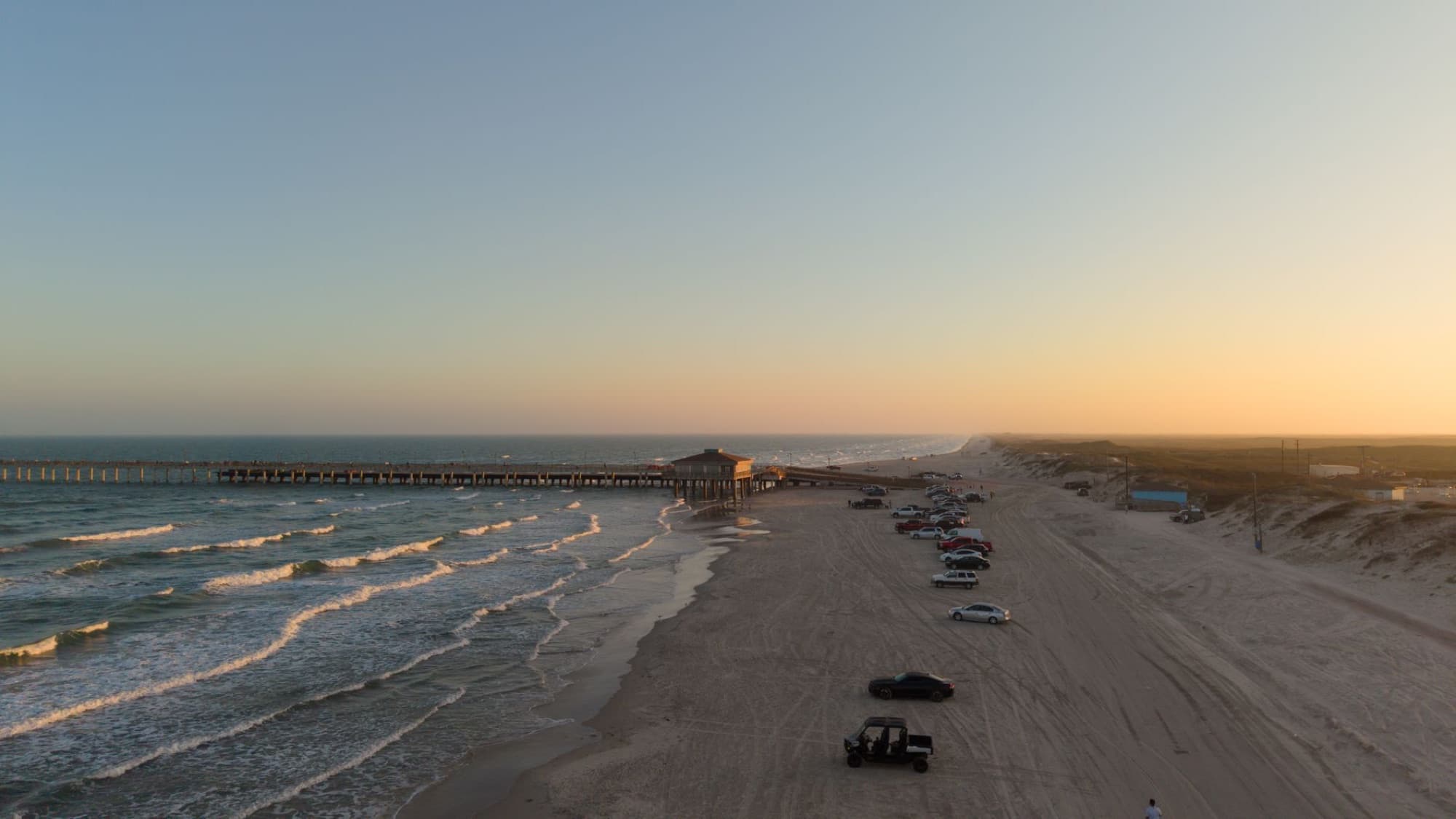 A stunning aerial view of Bob Hall Pier and Padre Balli Beach during sunset in Corpus Christi, Texas.