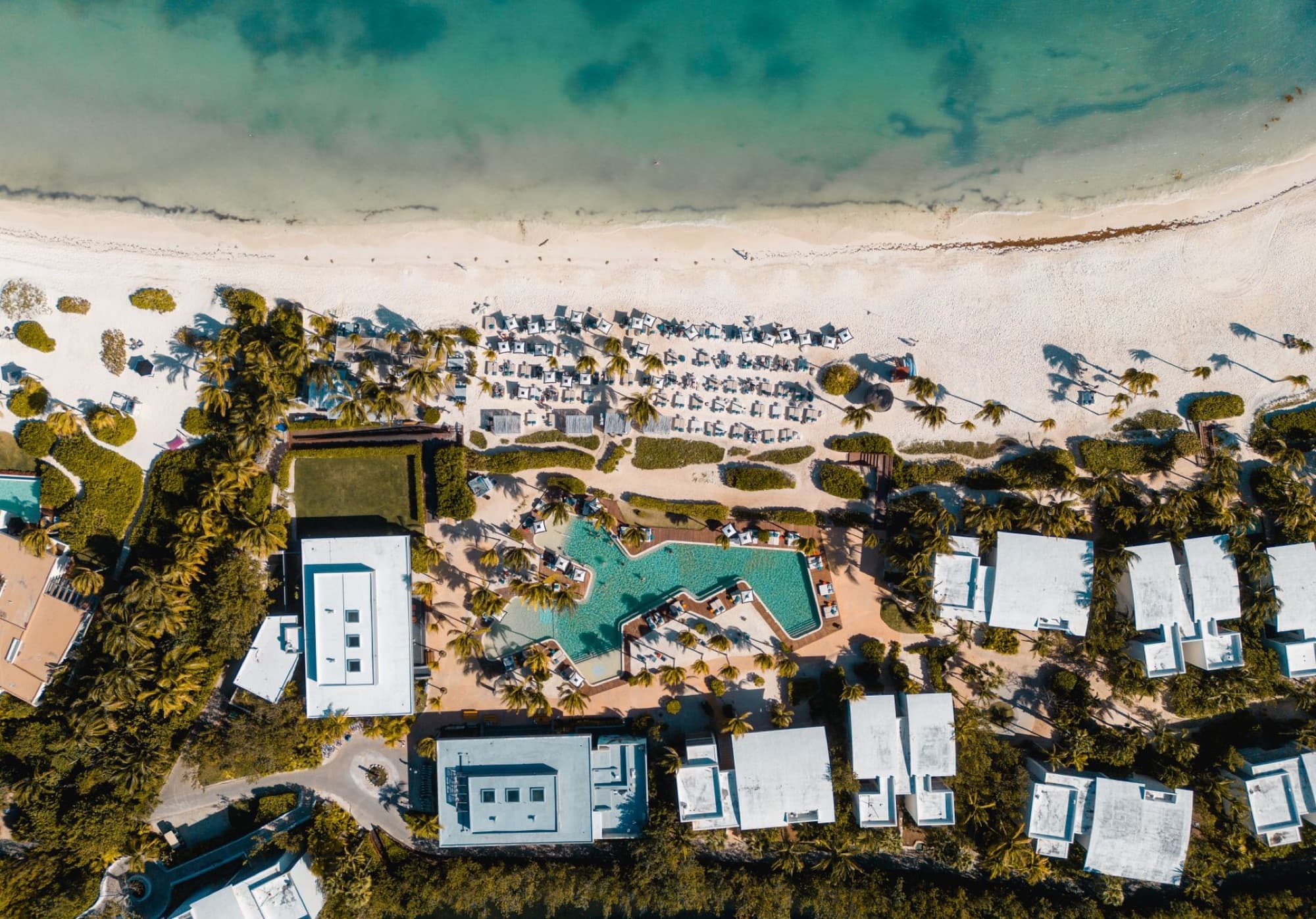 Stunning aerial view of Playa del Carmen with beach umbrellas and a resort pool in Mexico.