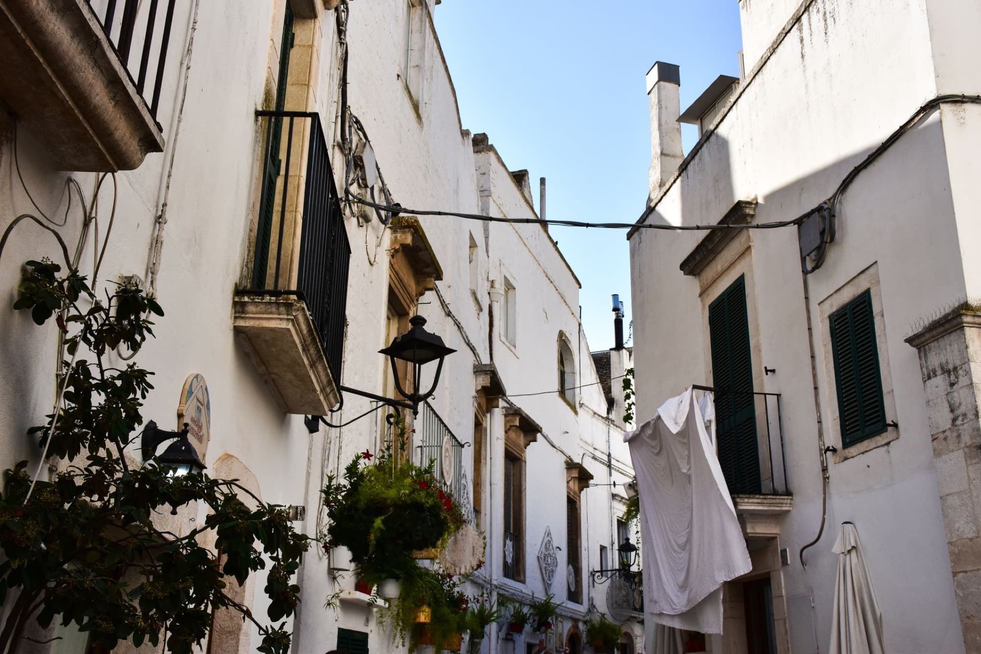 Picturesque narrow alley in Puglia with whitewashed buildings and vibrant flowers.