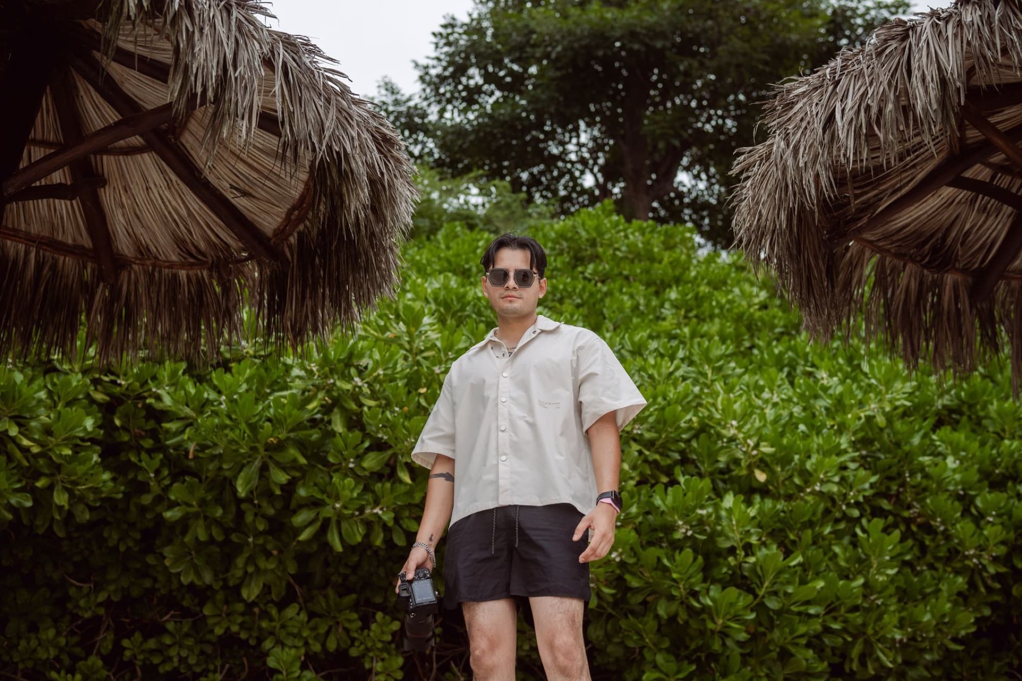 A photographer in beach attire holding a camera, surrounded by lush tropical greenery in Punta Mita.