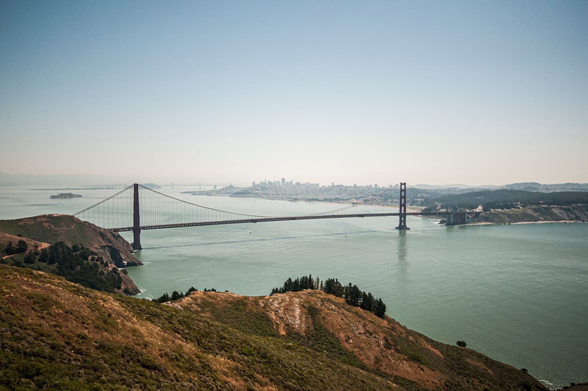 Aerial view of the Golden Gate Bridge spanning the San Francisco Bay with a clear skyline.