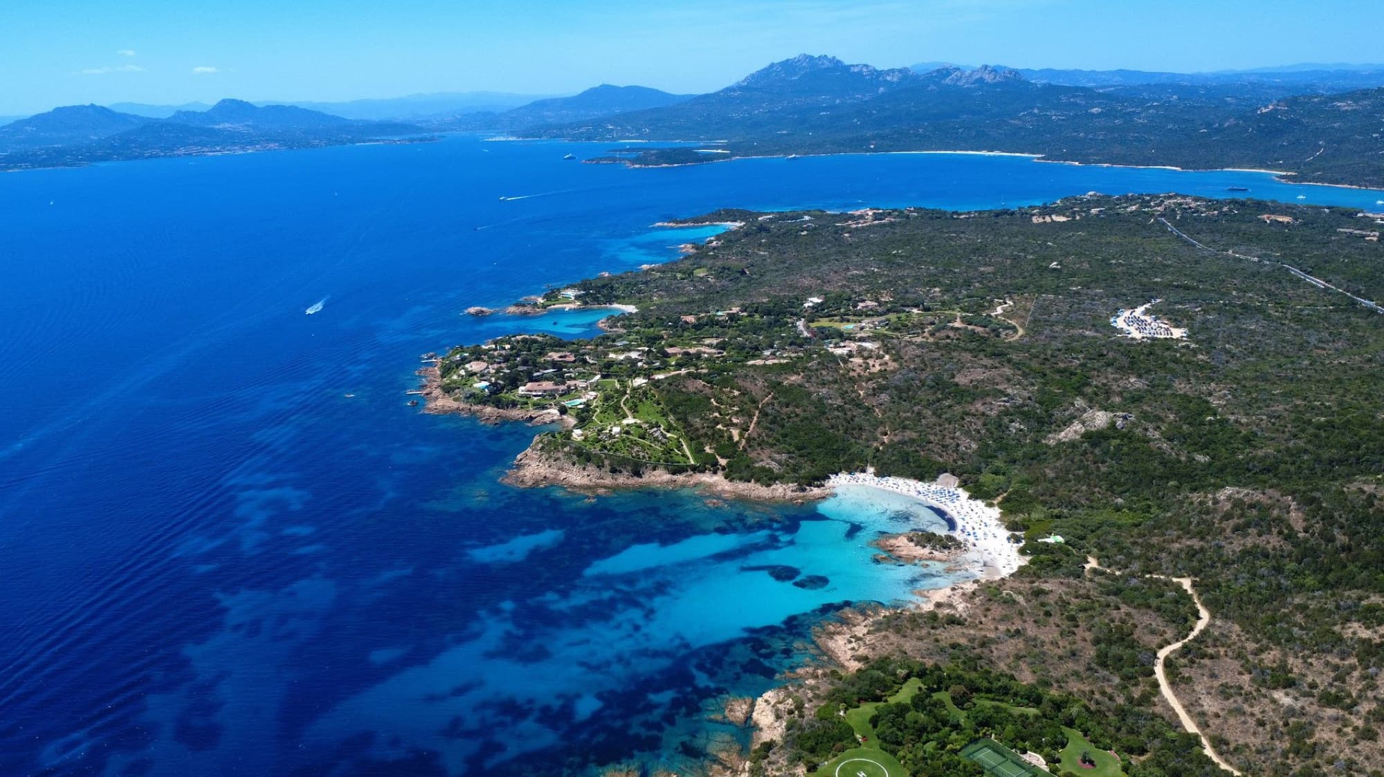 Breathtaking aerial view of Sardinia's stunning coastline with crystal-clear waters and lush greenery.