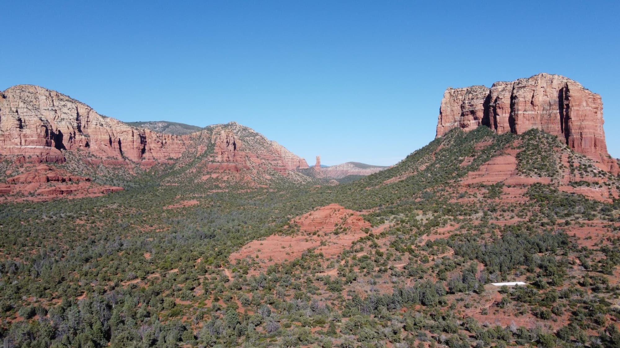 Breathtaking aerial shot of Sedona's iconic red rock landscape under a bright blue sky.