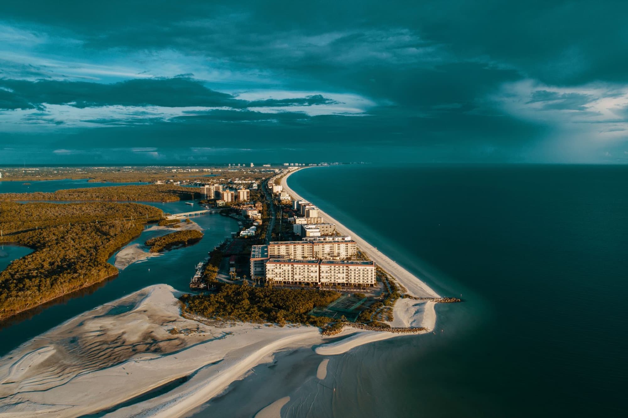 Breathtaking aerial view of a coastal city, featuring a scenic coastline and ocean vista under dramatic skies.