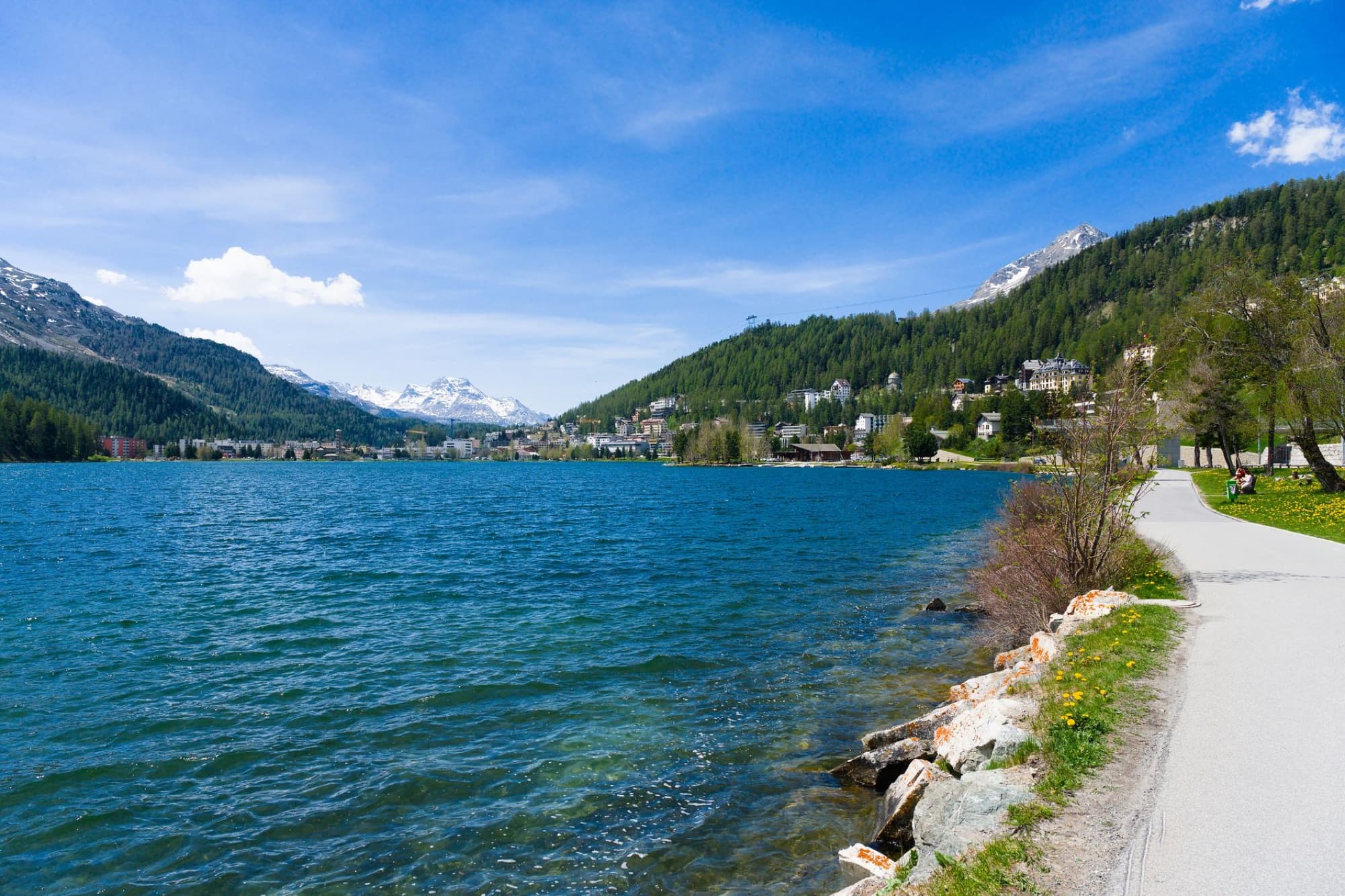 Beautiful lake and mountain landscape in St. Moritz, Switzerland under clear blue sky.