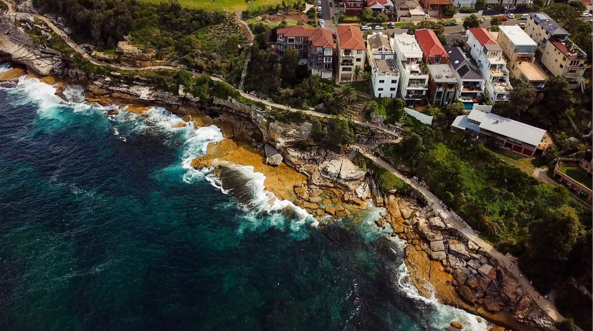 Stunning aerial shot of Bondi's coastline with homes and rugged cliffs, NSW, Australia.