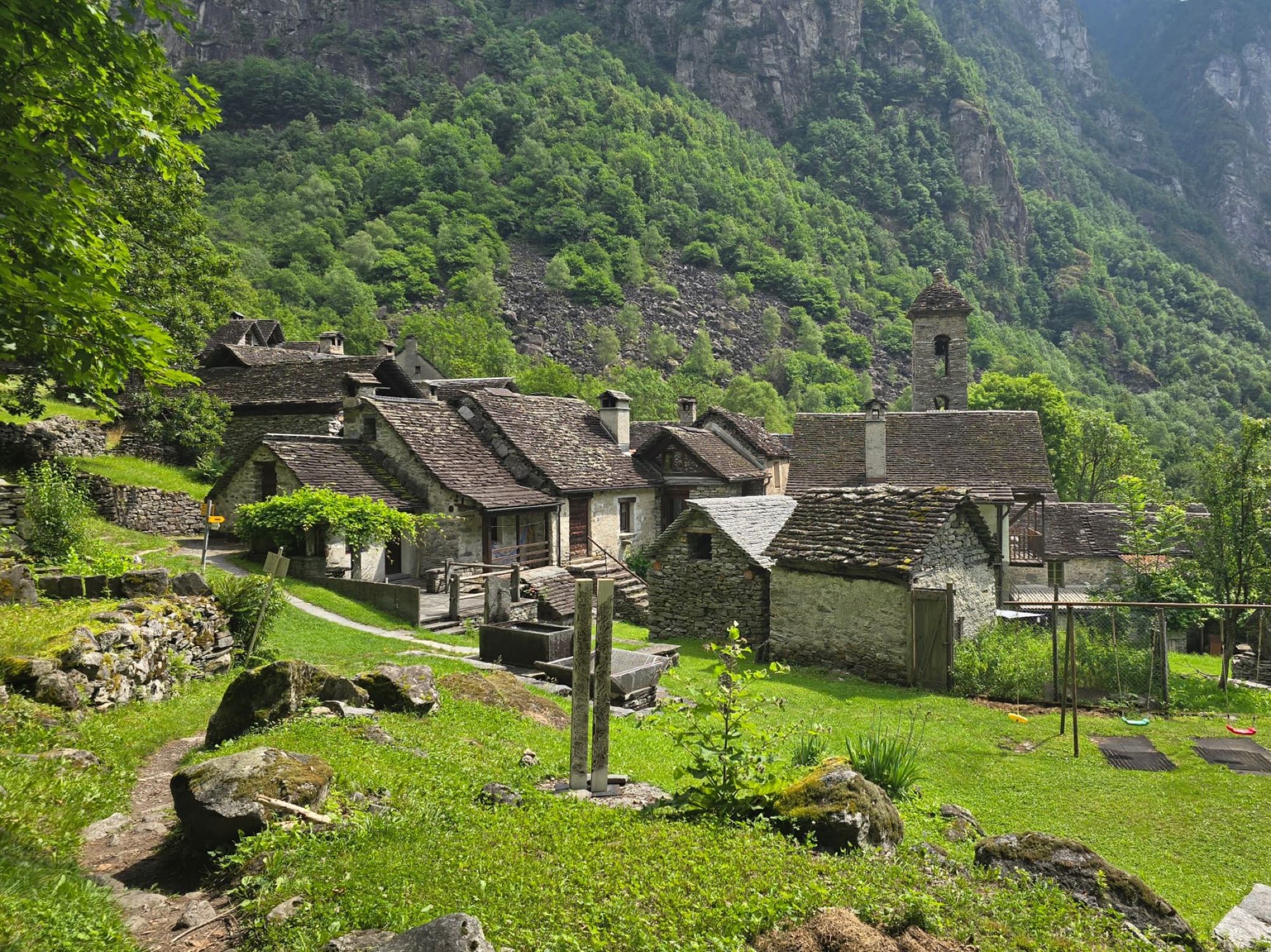 Picturesque Ticino village nestled in lush mountains, showcasing traditional stone houses and natural beauty.