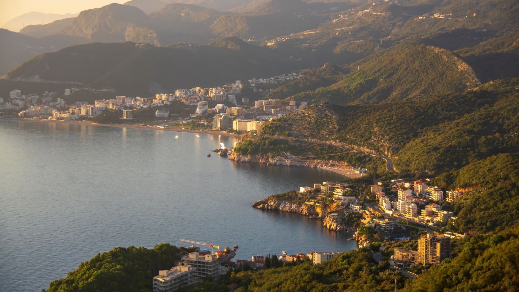 Stunning aerial view of a coastal town surrounded by mountains at sunset.